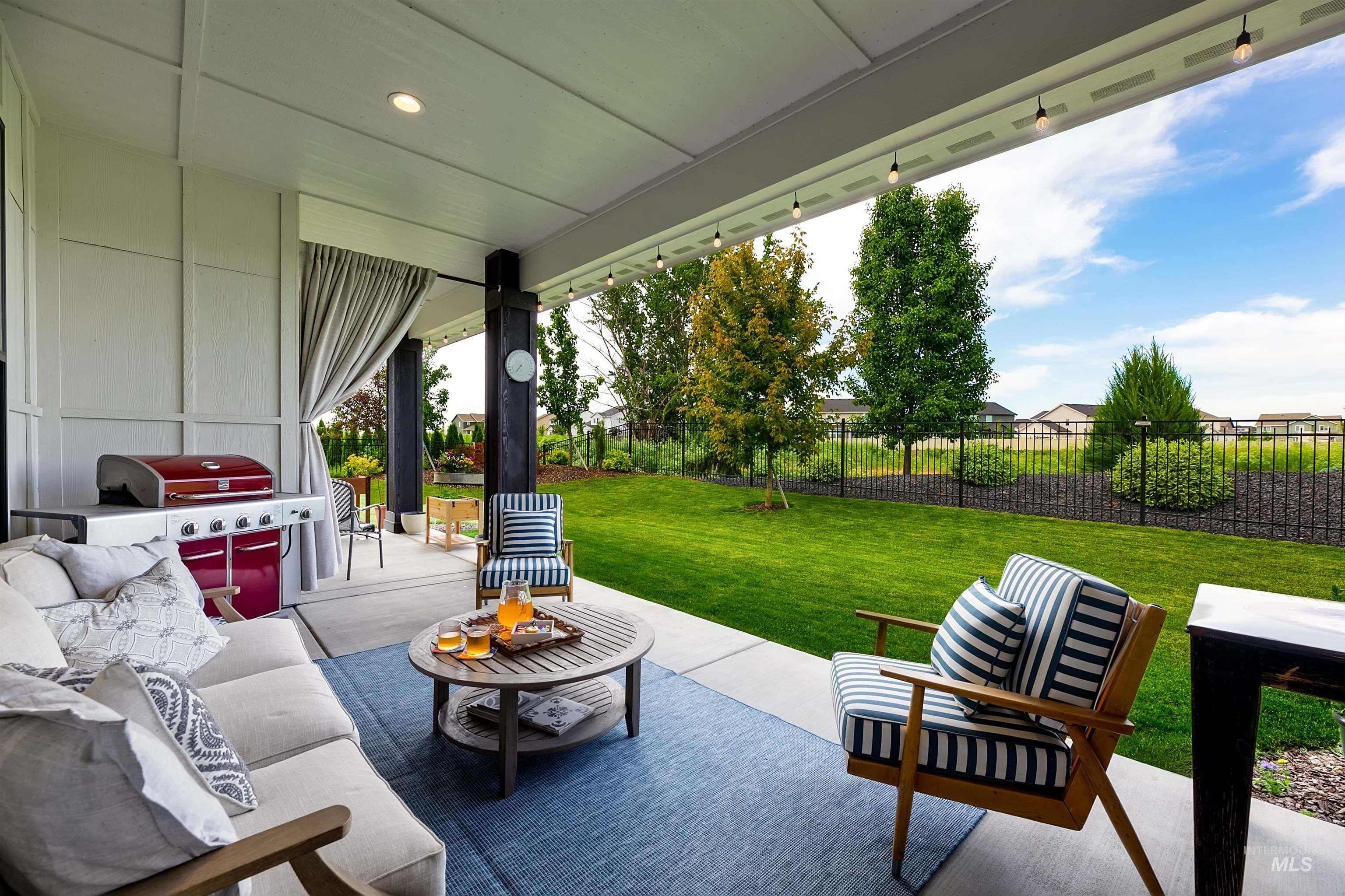 Covered patio with recessed lighting, bordered by a manicured lawn and mature trees