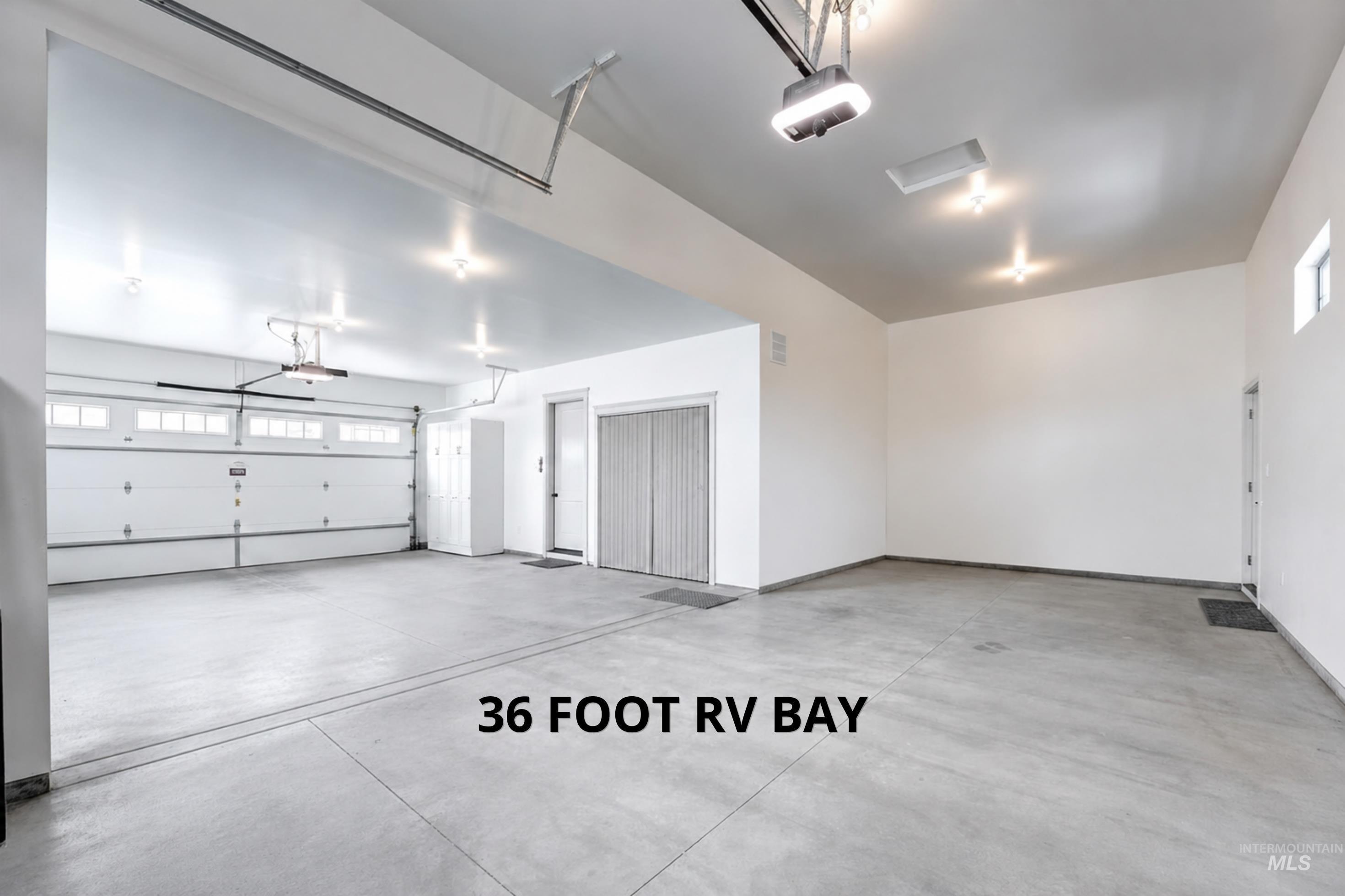 Spacious garage with high ceilings, concrete flooring, and multiple ceiling-mounted light fixtures