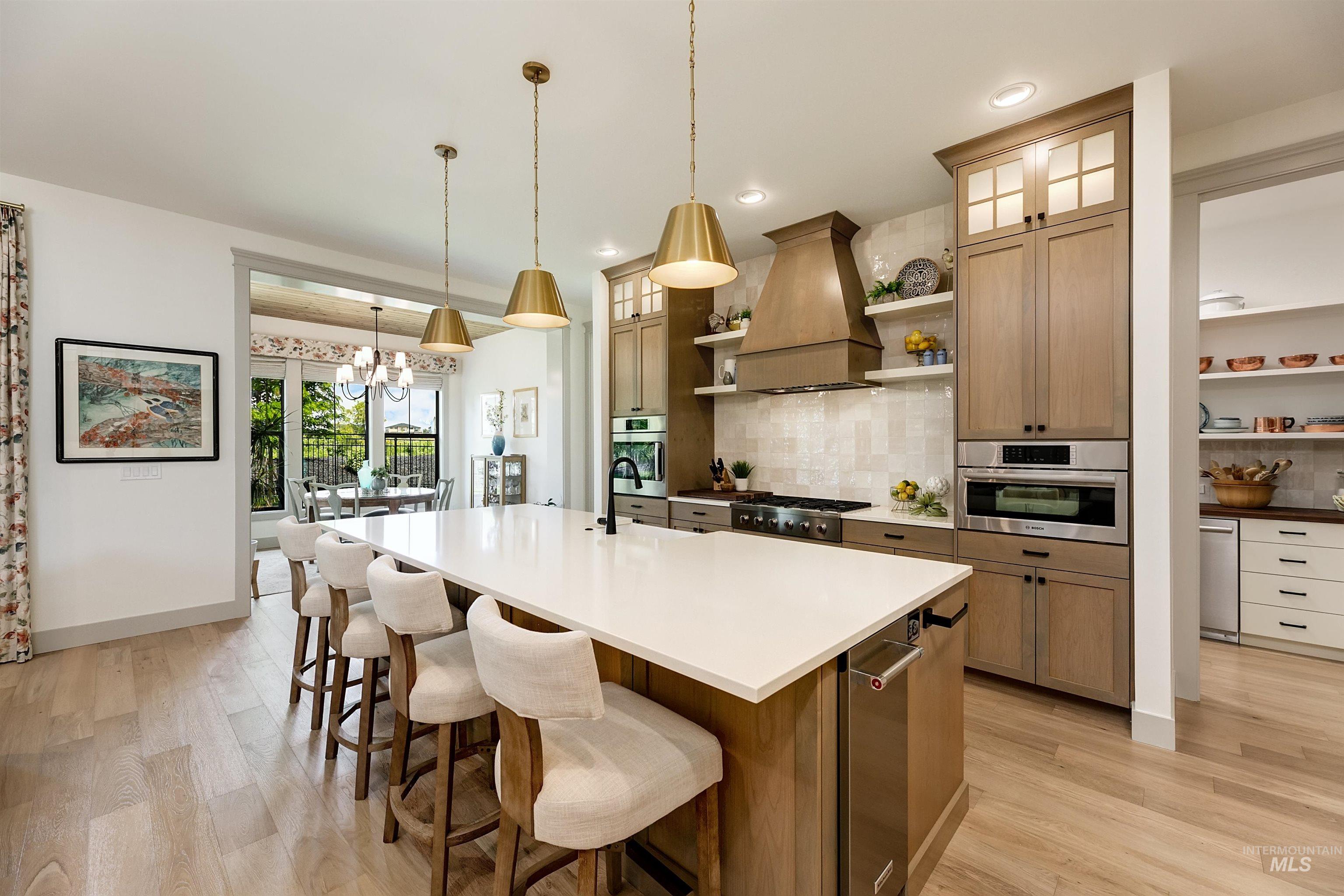Gourmet kitchen with a large central island featuring a white countertop and built-in dishwasher