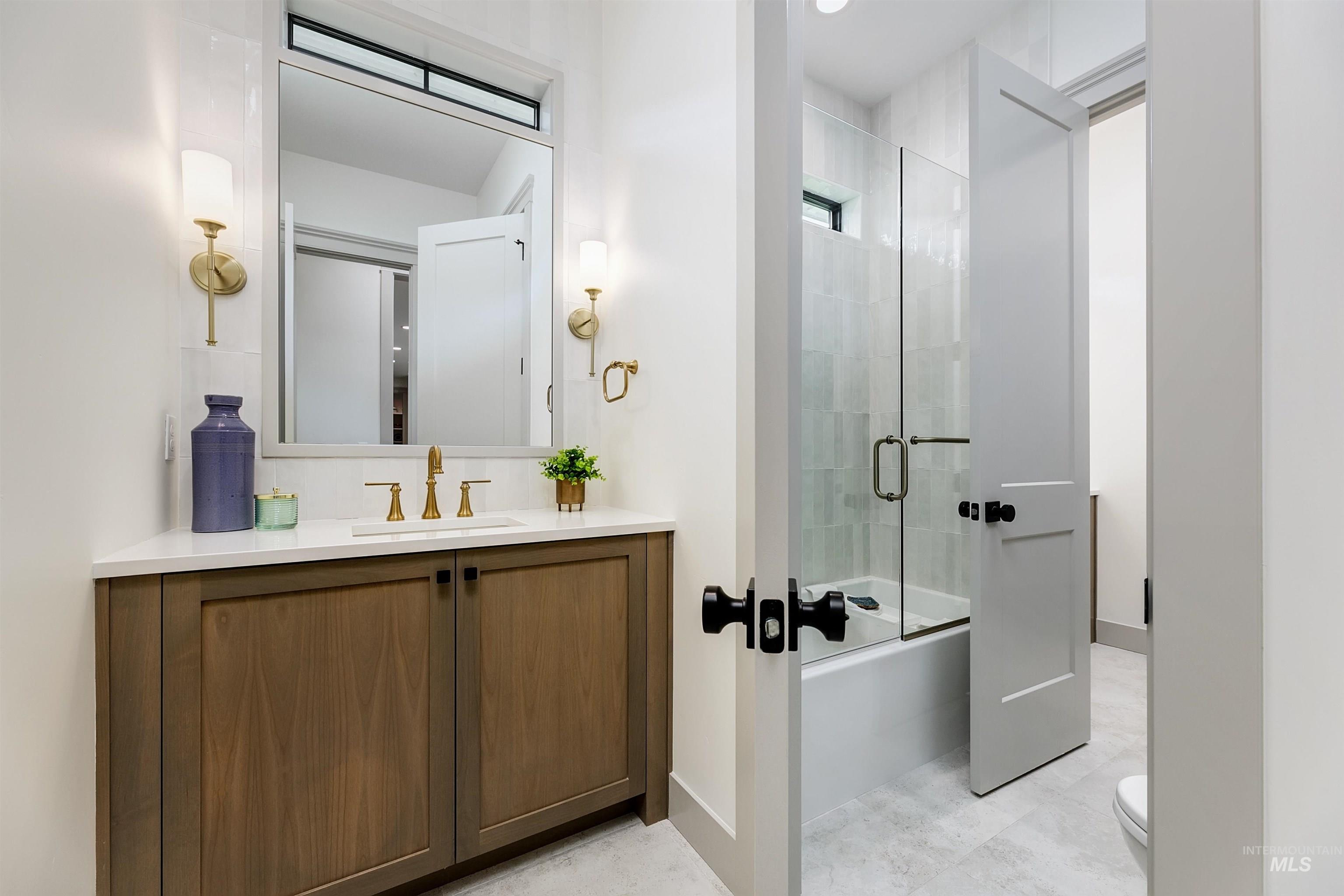 Bathroom featuring a wood-finish vanity with a light-toned countertop and an undermount sink