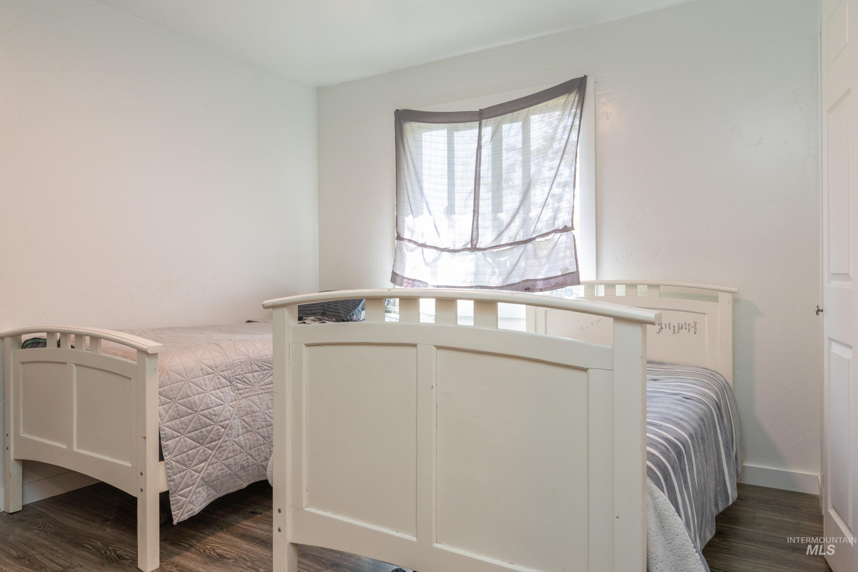 Bedroom featuring dark wood-style flooring and baseboards