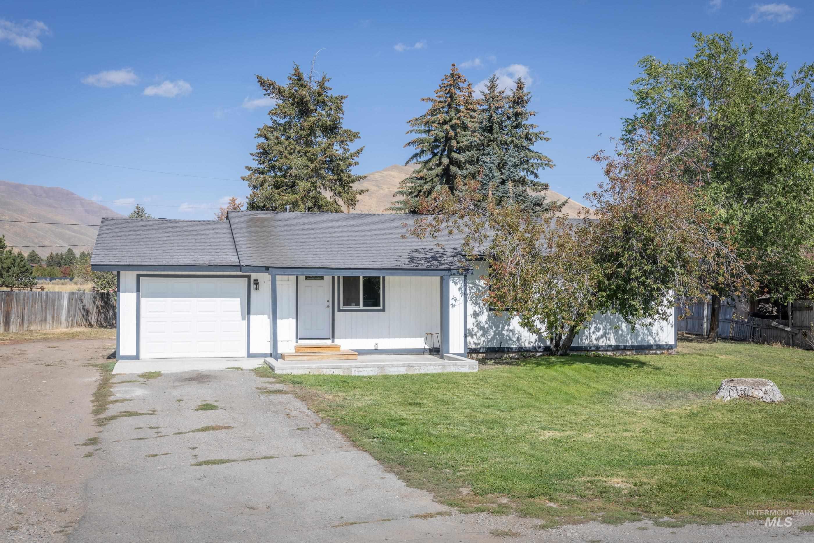 Single story home featuring covered porch, a mountain view, asphalt driveway, an attached garage, and a shingled roof