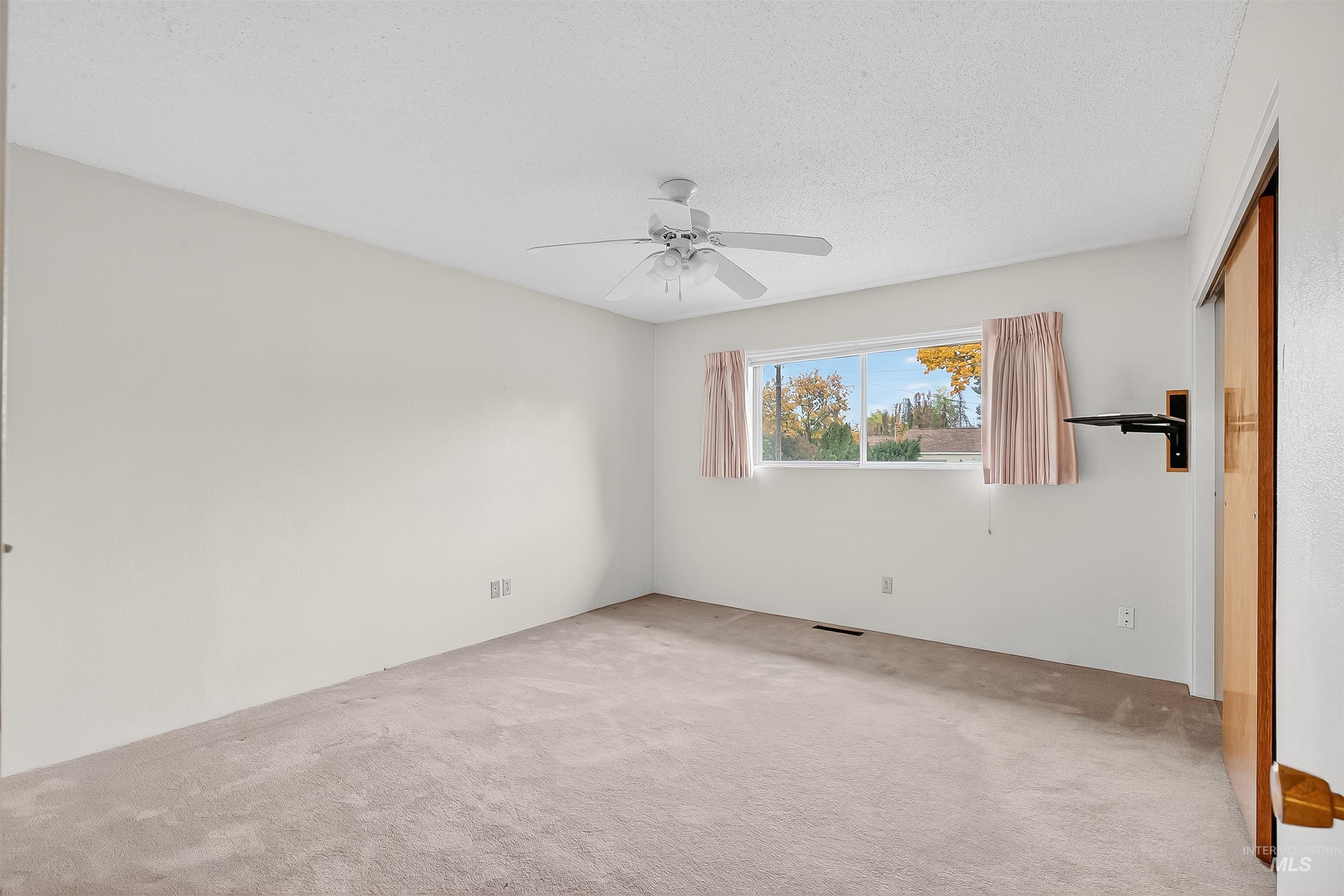 Unfurnished bedroom featuring a closet, carpet flooring, a ceiling fan, and a textured ceiling