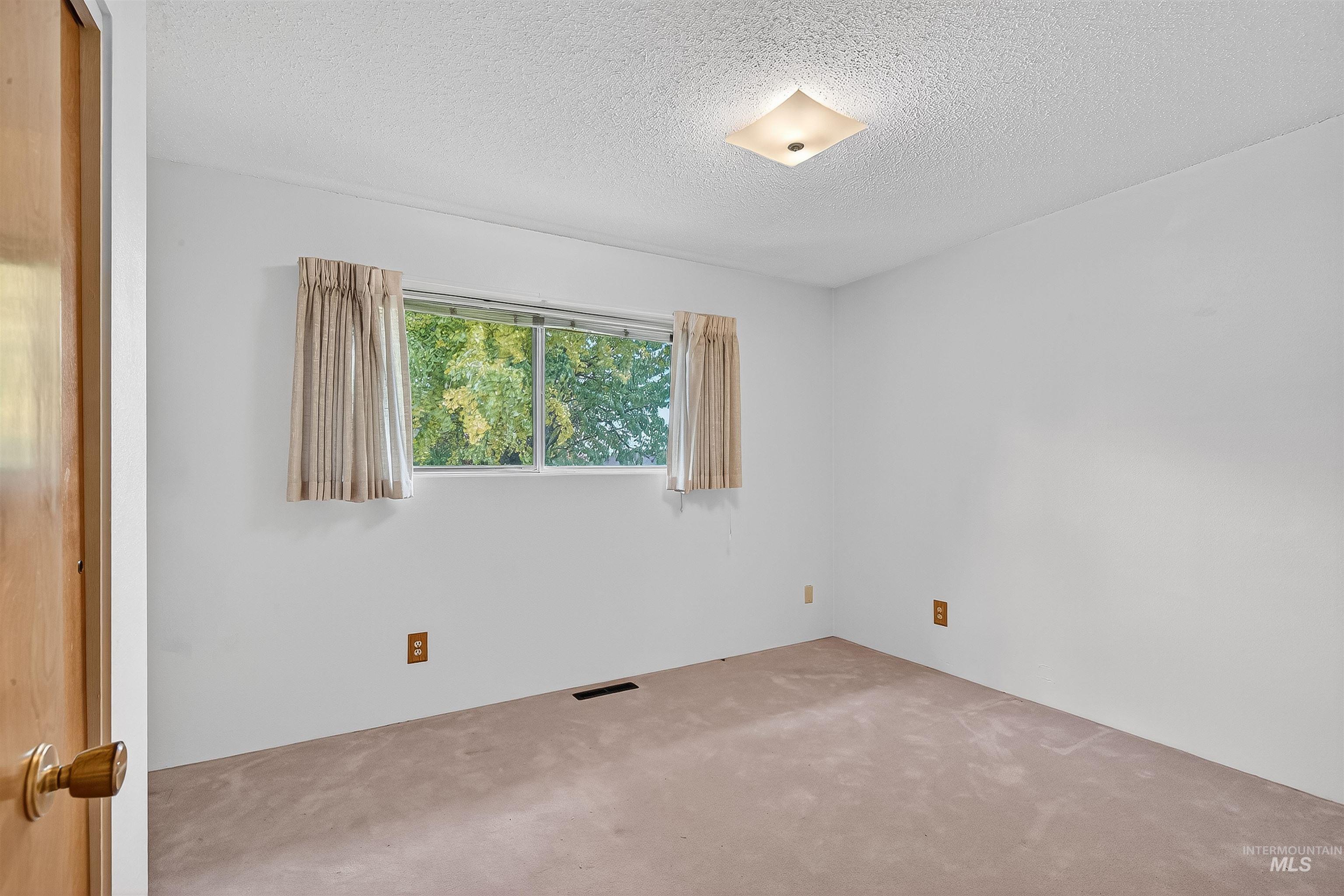 Carpeted spare room featuring a textured ceiling