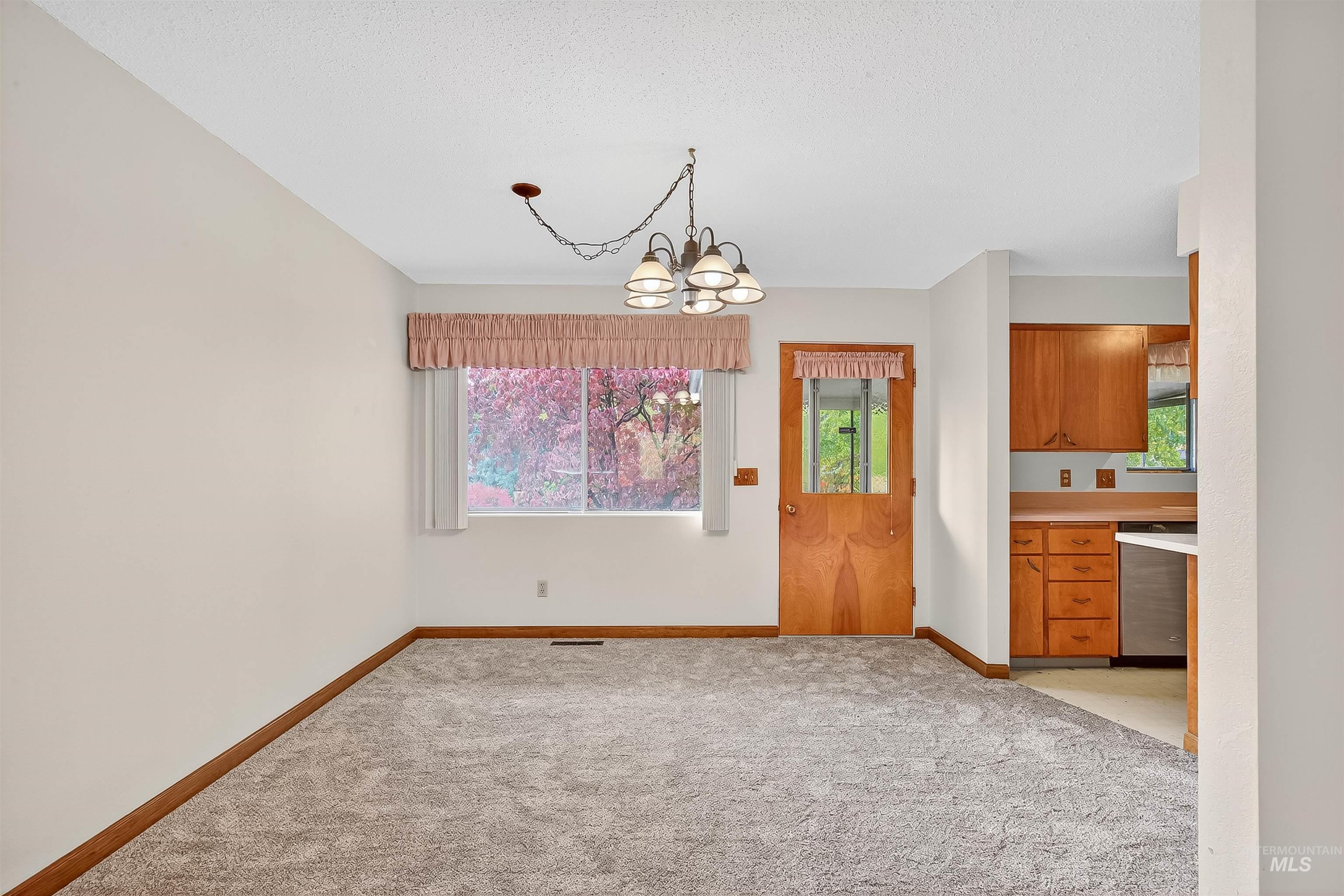 Unfurnished dining area with light carpet and a chandelier