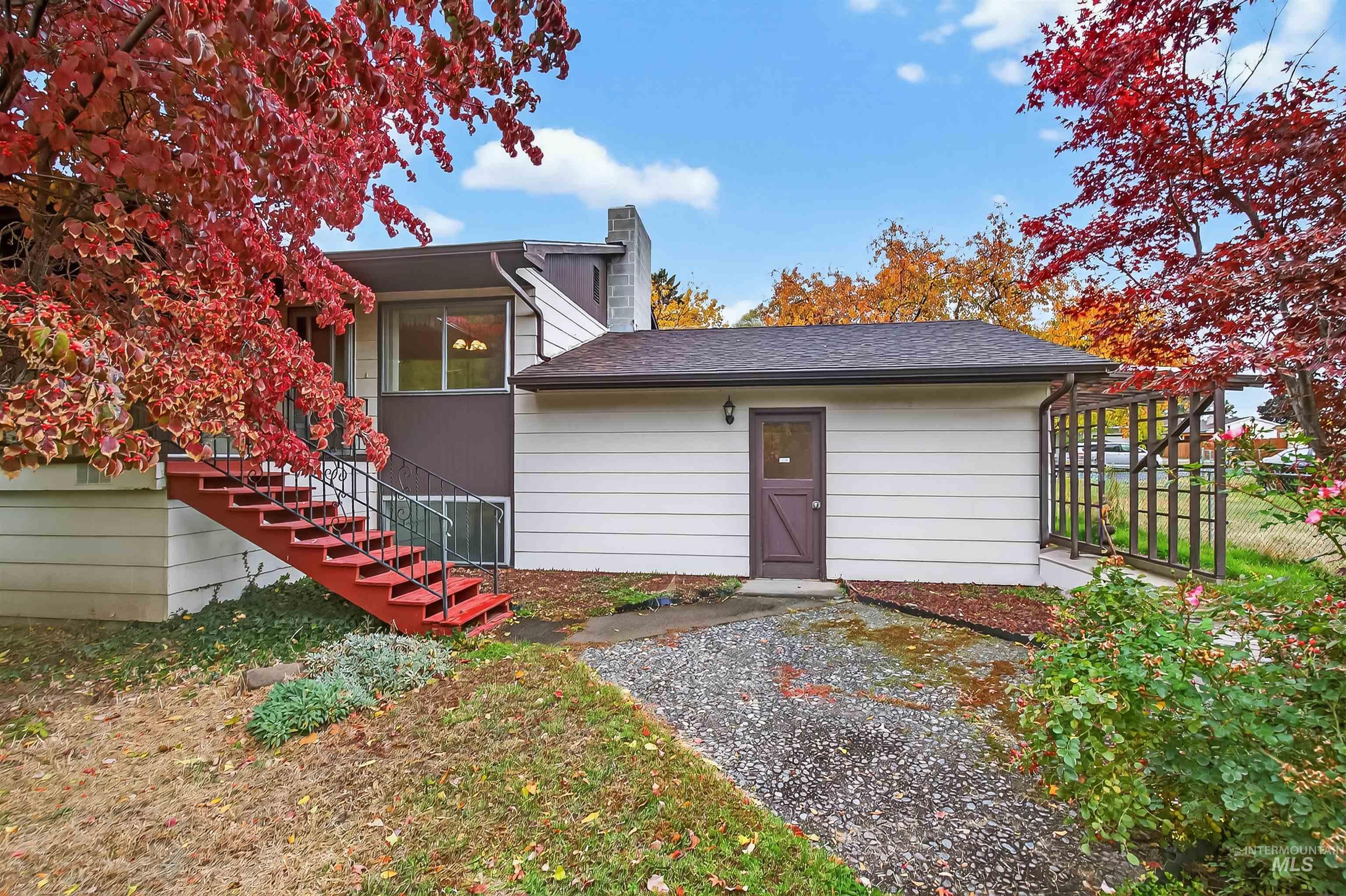 Back of house with stairs, a chimney, and roof with shingles
