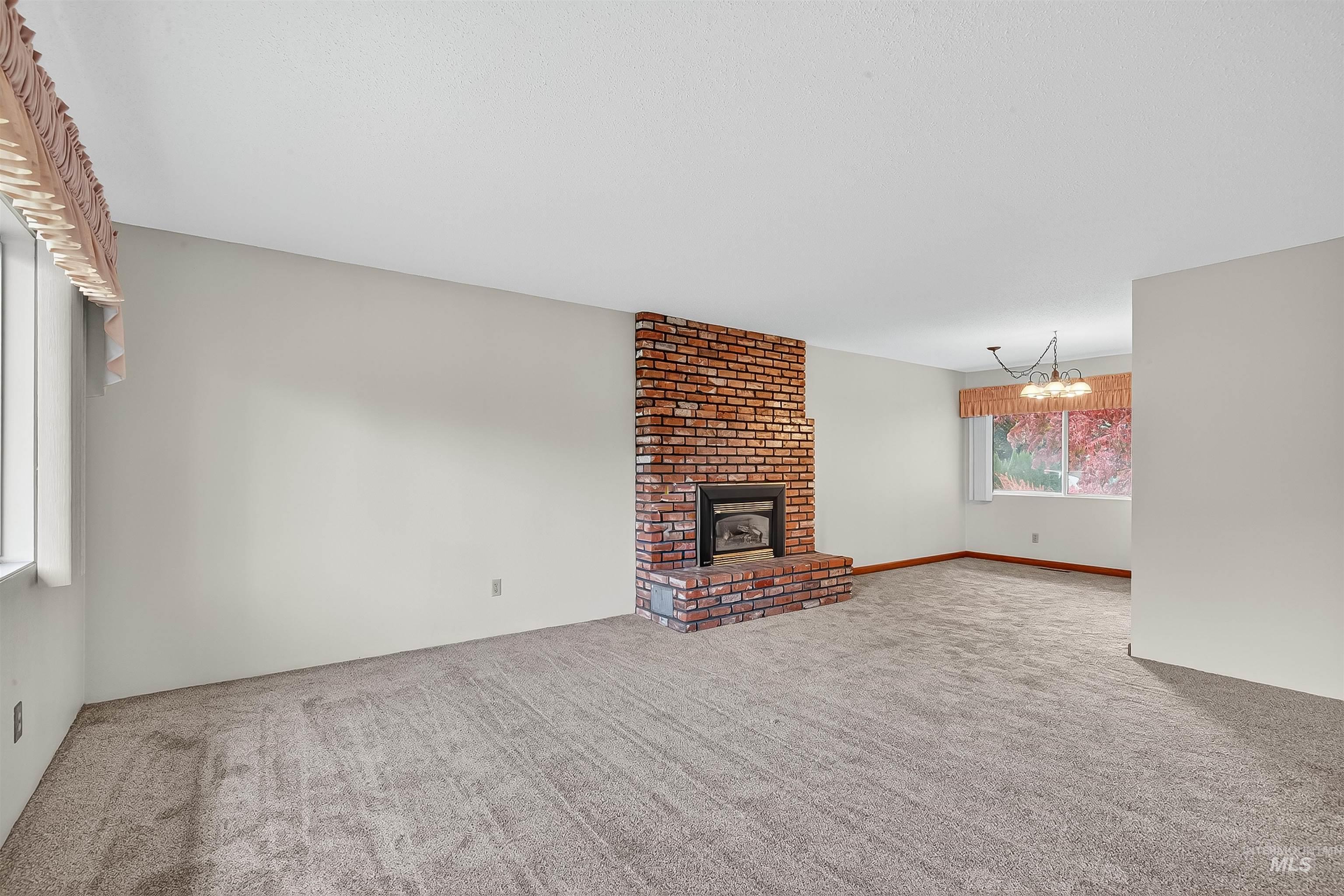 Unfurnished living room with carpet, a fireplace, and a chandelier