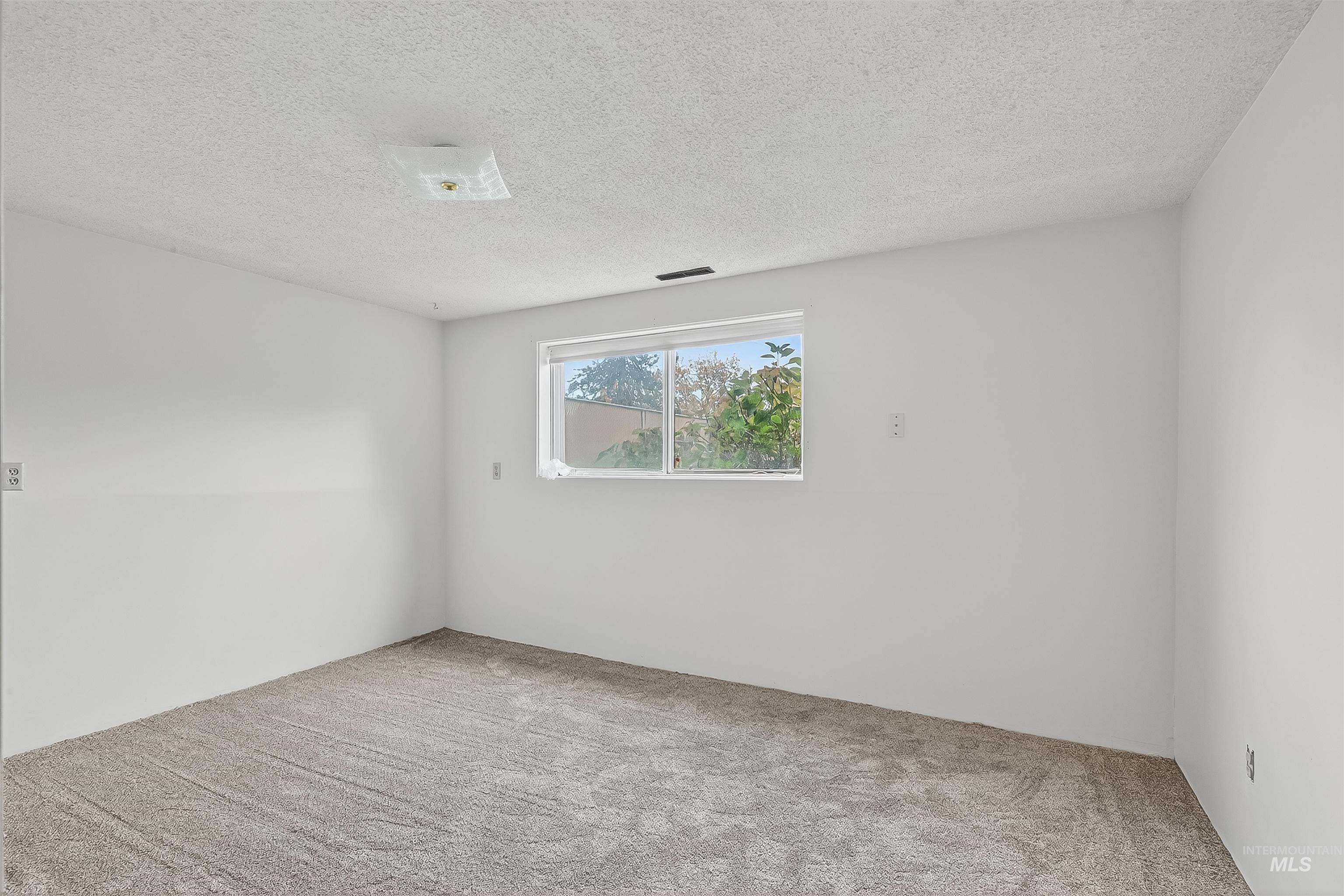 Carpeted empty room with a textured ceiling