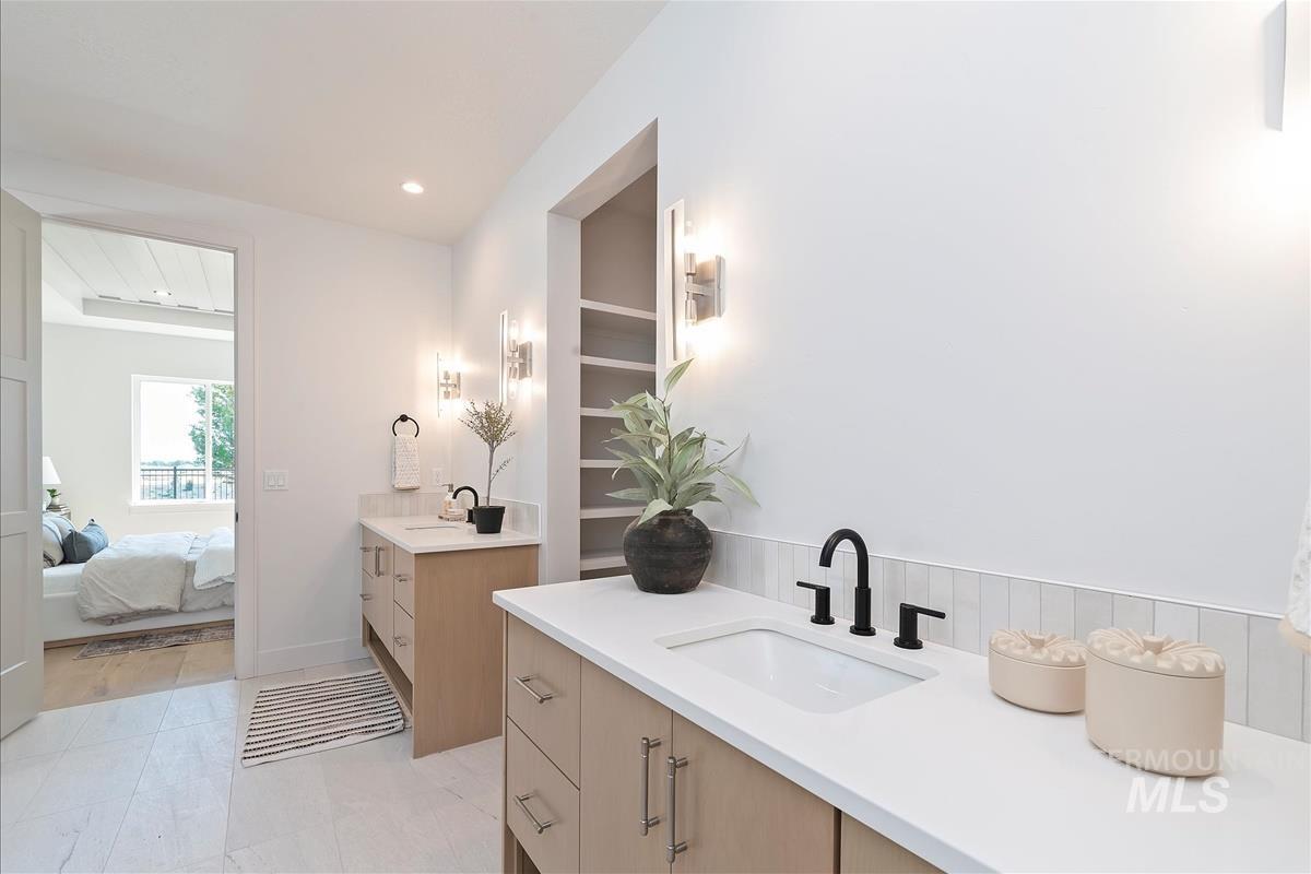 Full bathroom featuring two vanities, recessed lighting, and connected bathroom