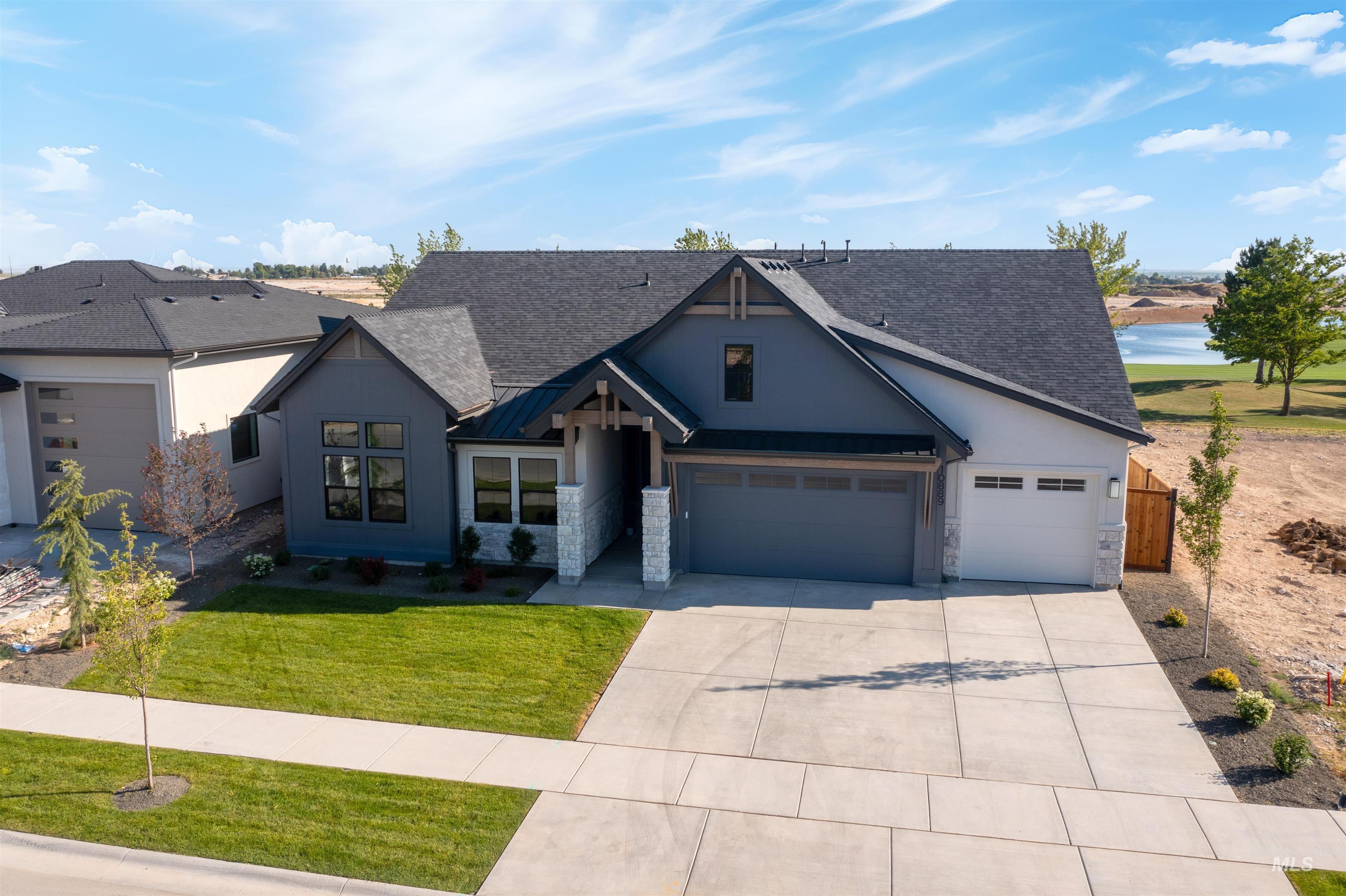 View of front of house featuring stucco siding, concrete driveway, roof with shingles, and stone siding