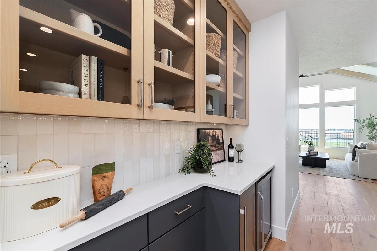 Bar area featuring wine cooler, light wood-style flooring, and tasteful backsplash