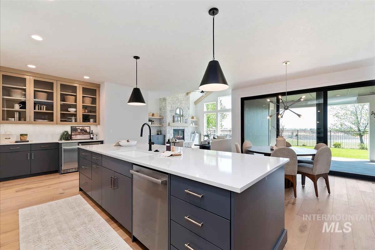 Kitchen featuring stainless steel dishwasher, light wood-style flooring, light countertops, pendant lighting, and recessed lighting