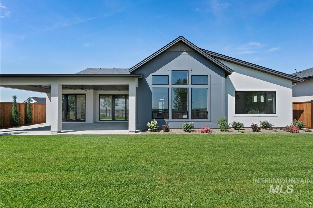 Rear view of house with stucco siding, a patio area, ceiling fan, and a carport