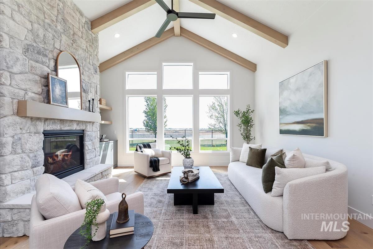 Living room with beam ceiling, wood finished floors, a fireplace, a ceiling fan, and high vaulted ceiling