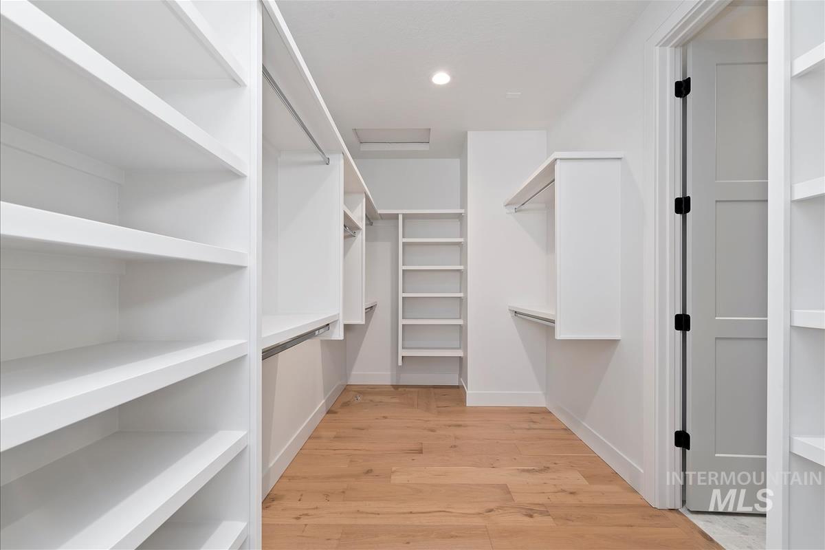 Spacious closet with light wood finished floors and attic access