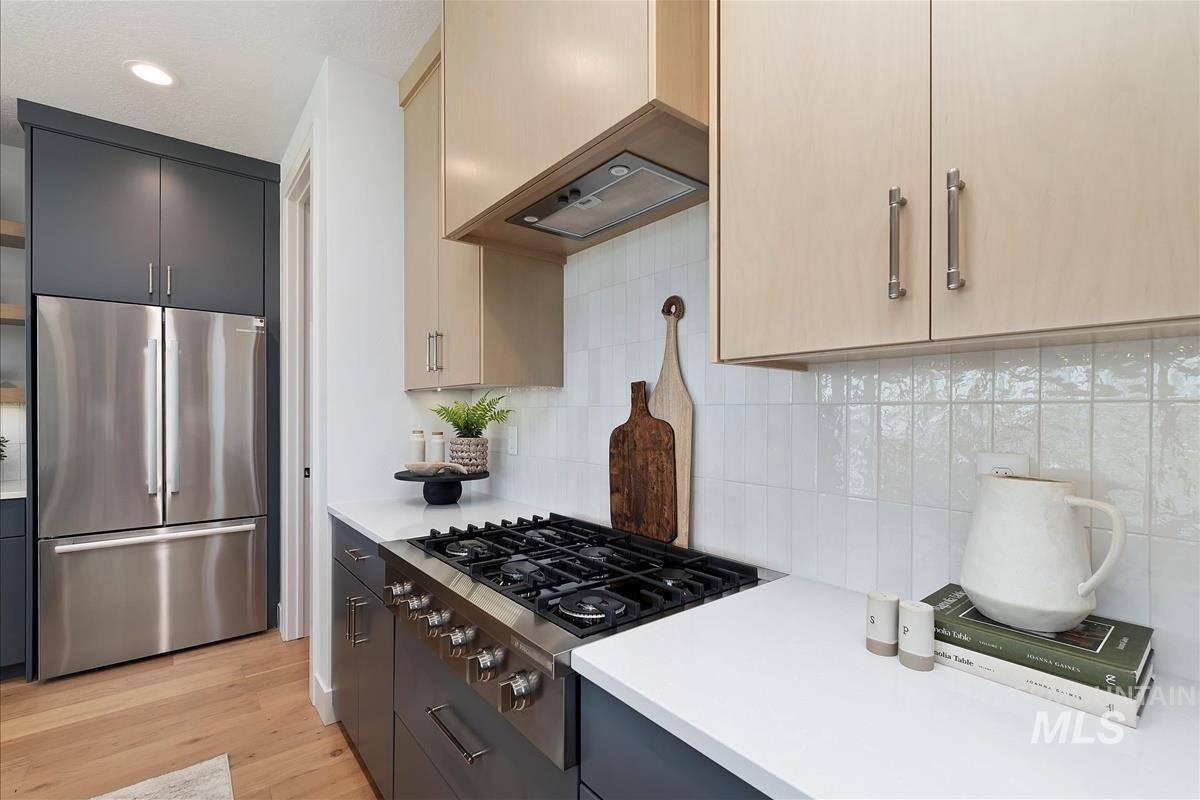 Kitchen featuring stainless steel appliances, light countertops, light wood finished floors, decorative backsplash, and recessed lighting