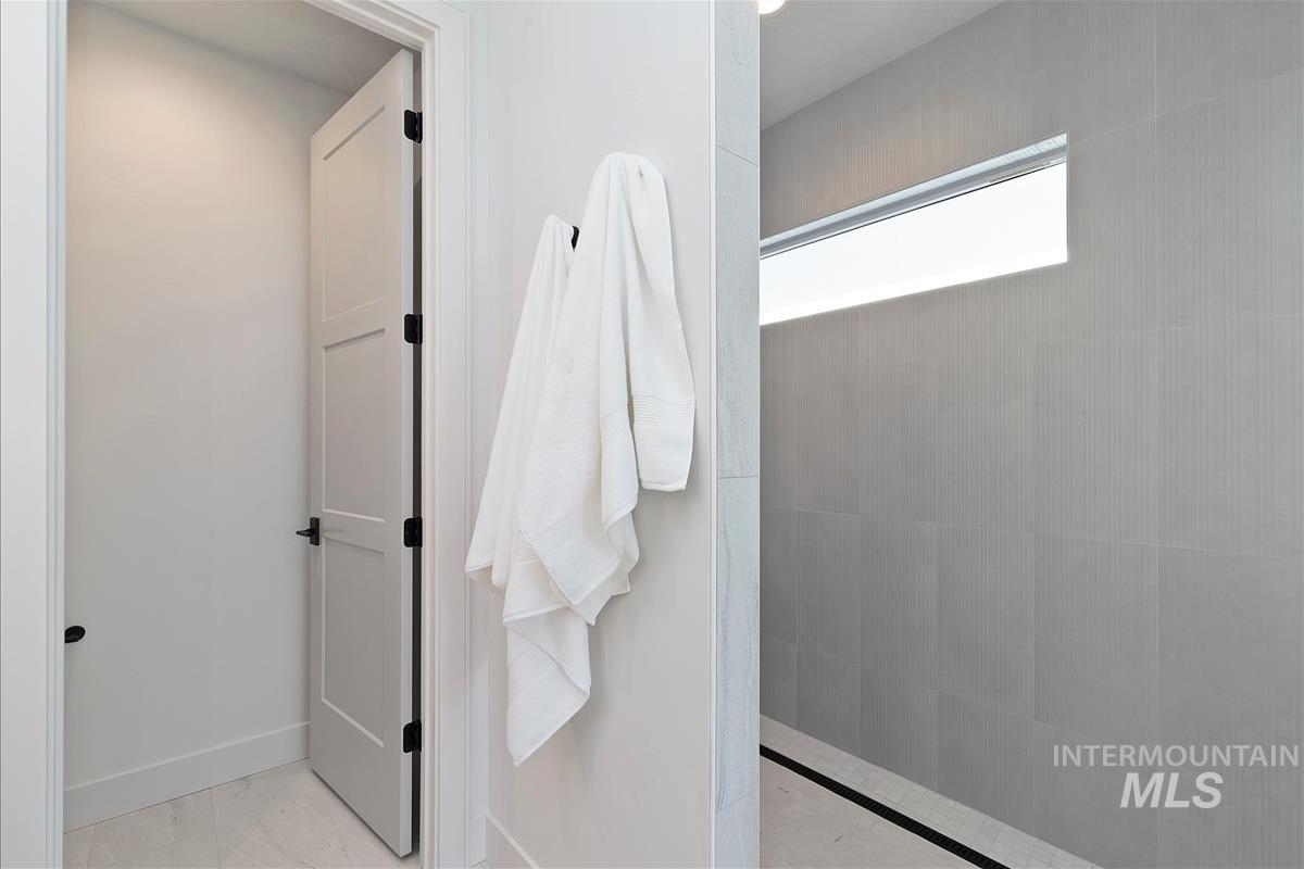 Full bath featuring a walk in shower and marble look tile flooring