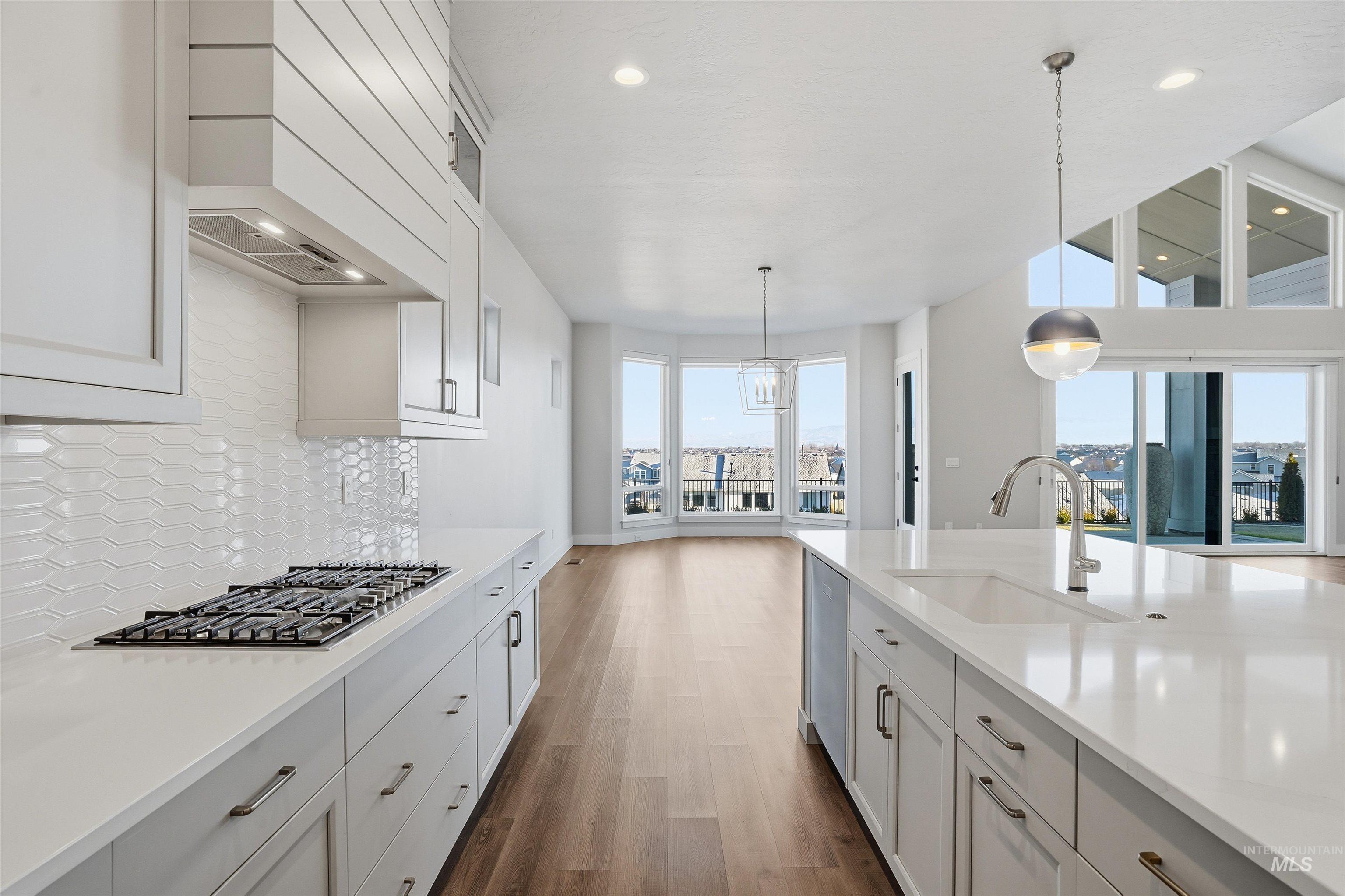 Kitchen with dark wood finished floors, decorative light fixtures, recessed lighting, stainless steel appliances, and white cabinets
