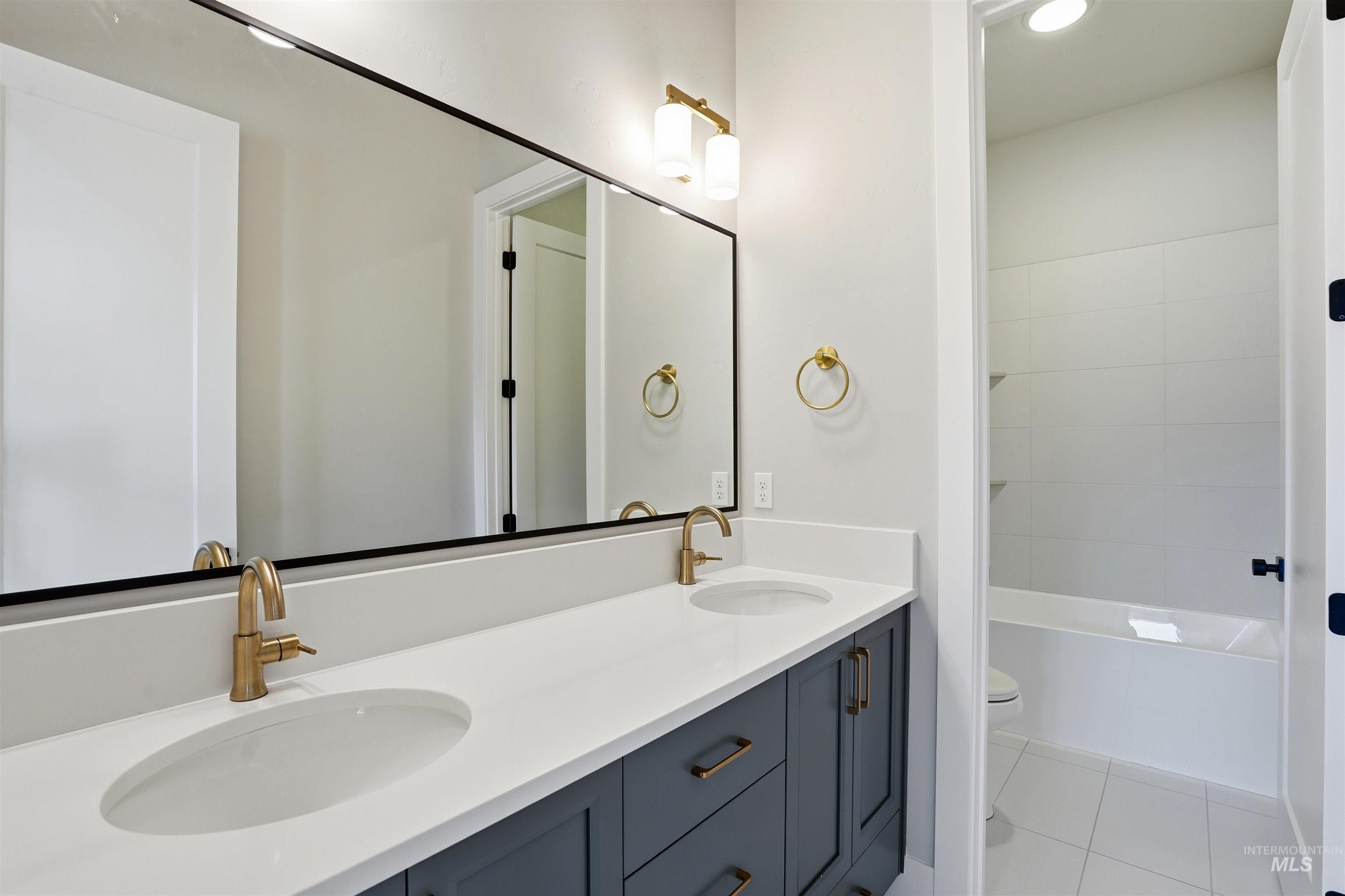Bathroom featuring double vanity, light tile patterned flooring, and bathing tub / shower combination