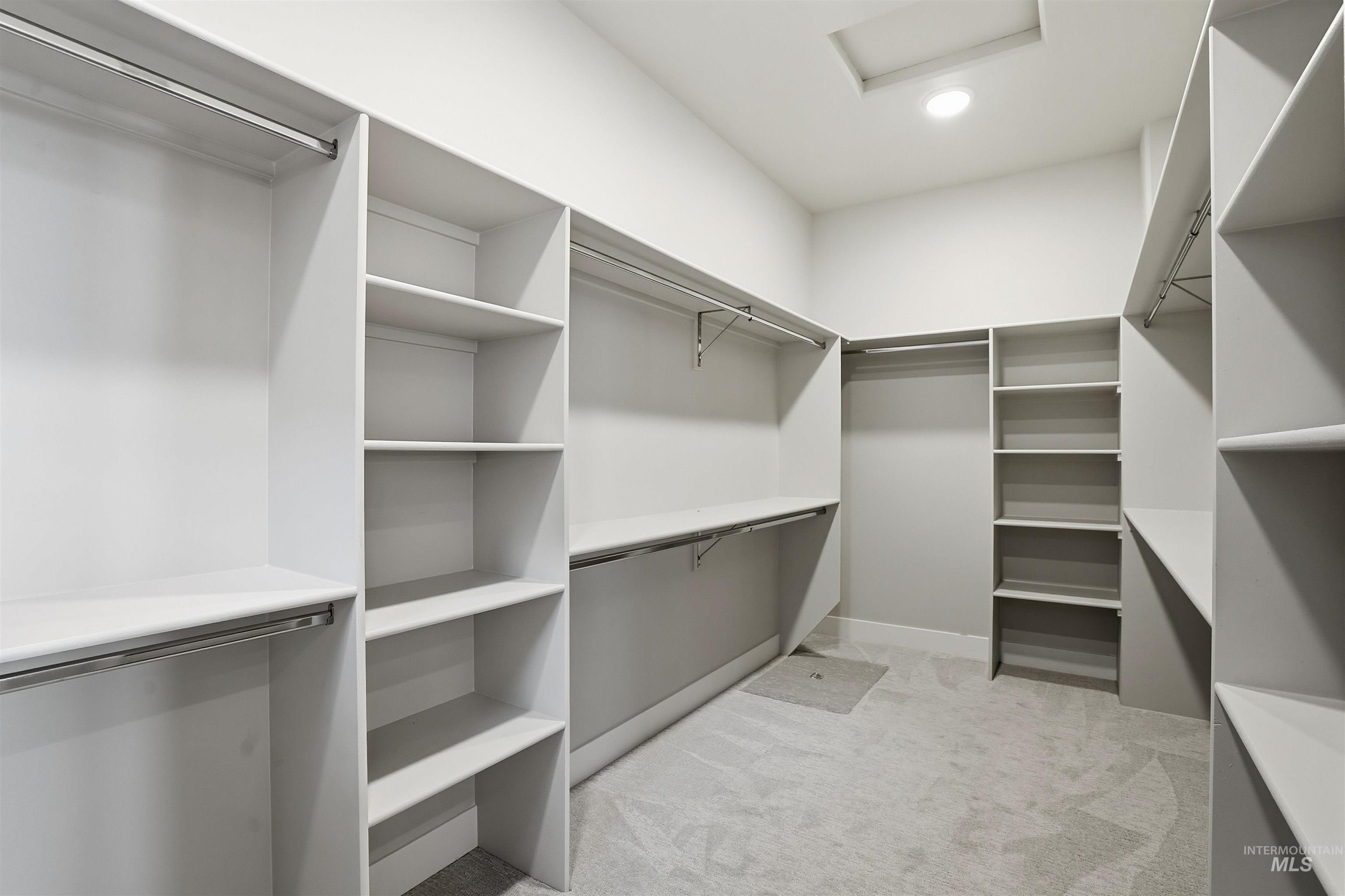 Walk in closet with light colored carpet and attic access