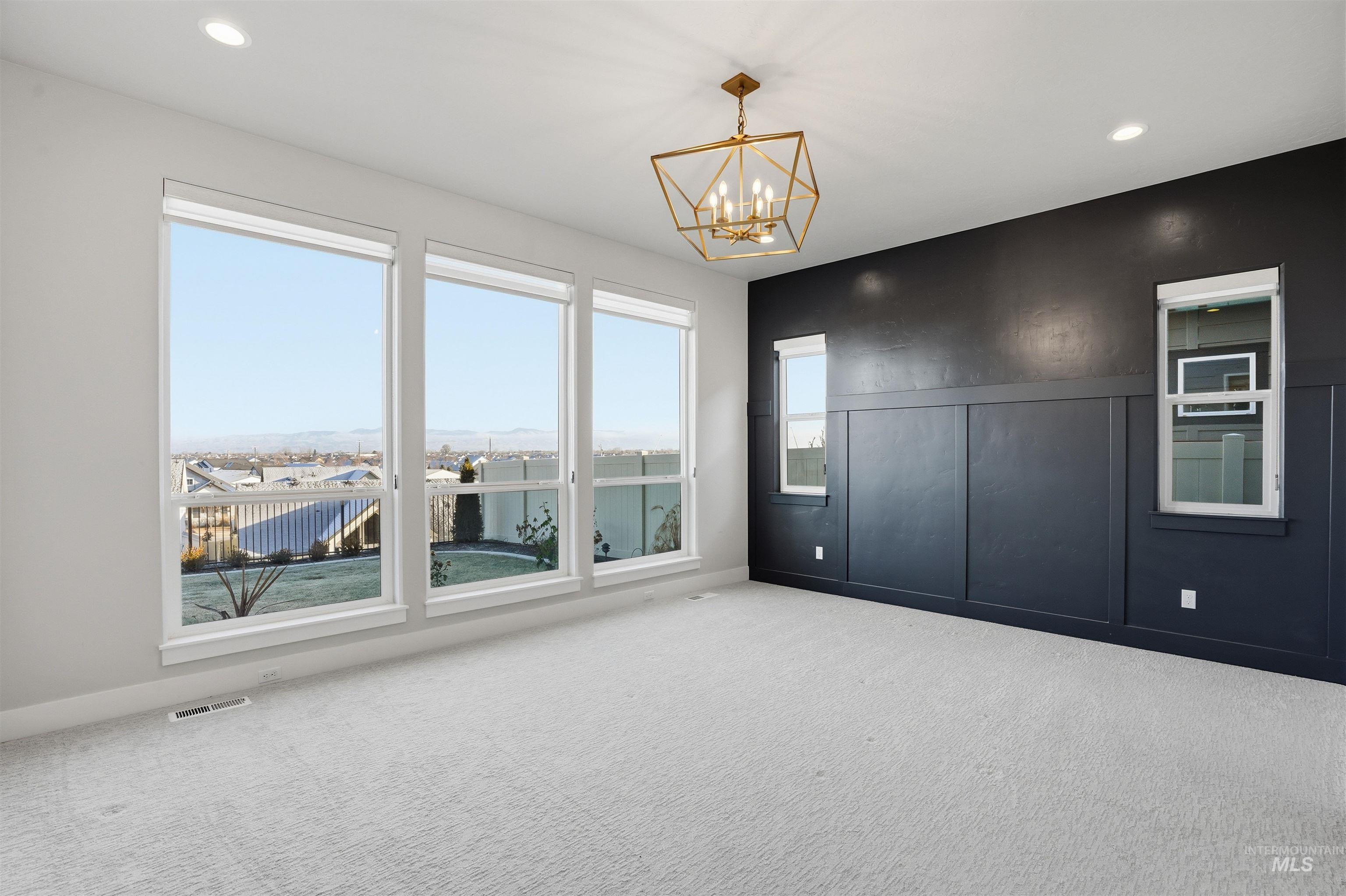 Empty room featuring carpet, recessed lighting, a chandelier, and a decorative wall