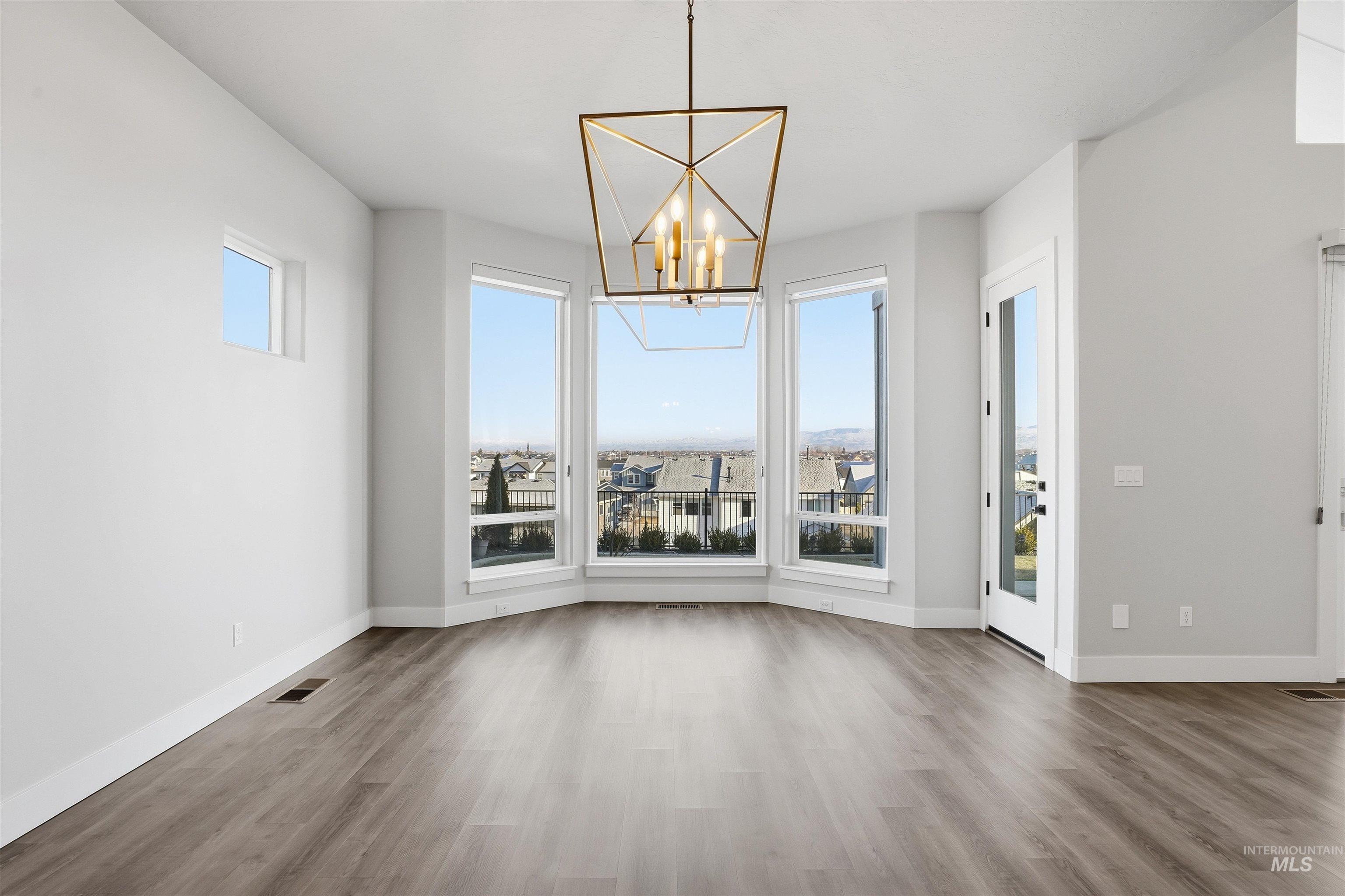 Unfurnished dining area featuring a chandelier and wood finished floors