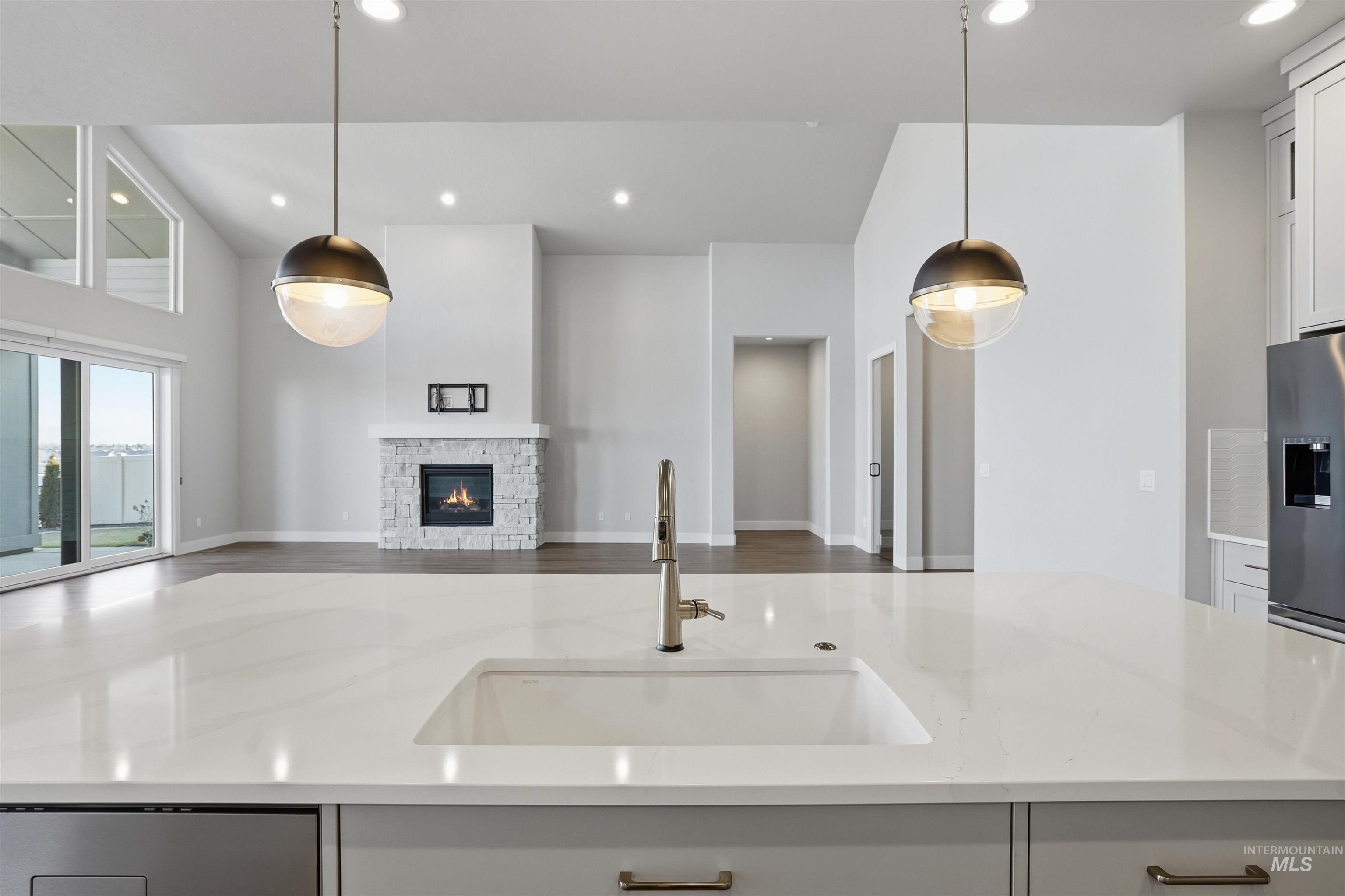 Kitchen featuring light stone countertops, open floor plan, a fireplace, recessed lighting, and white cabinetry