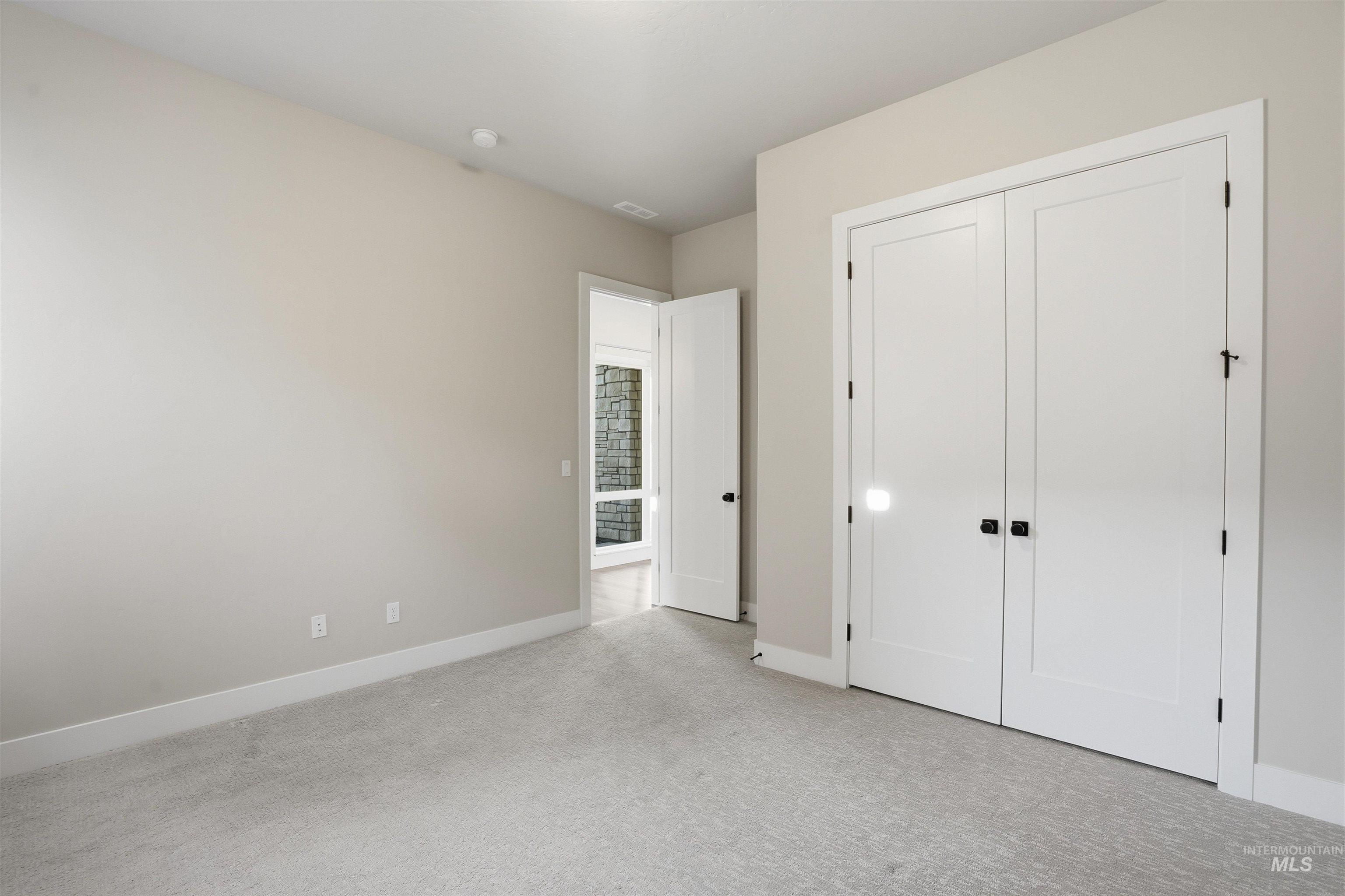 Unfurnished bedroom with light carpet and a closet