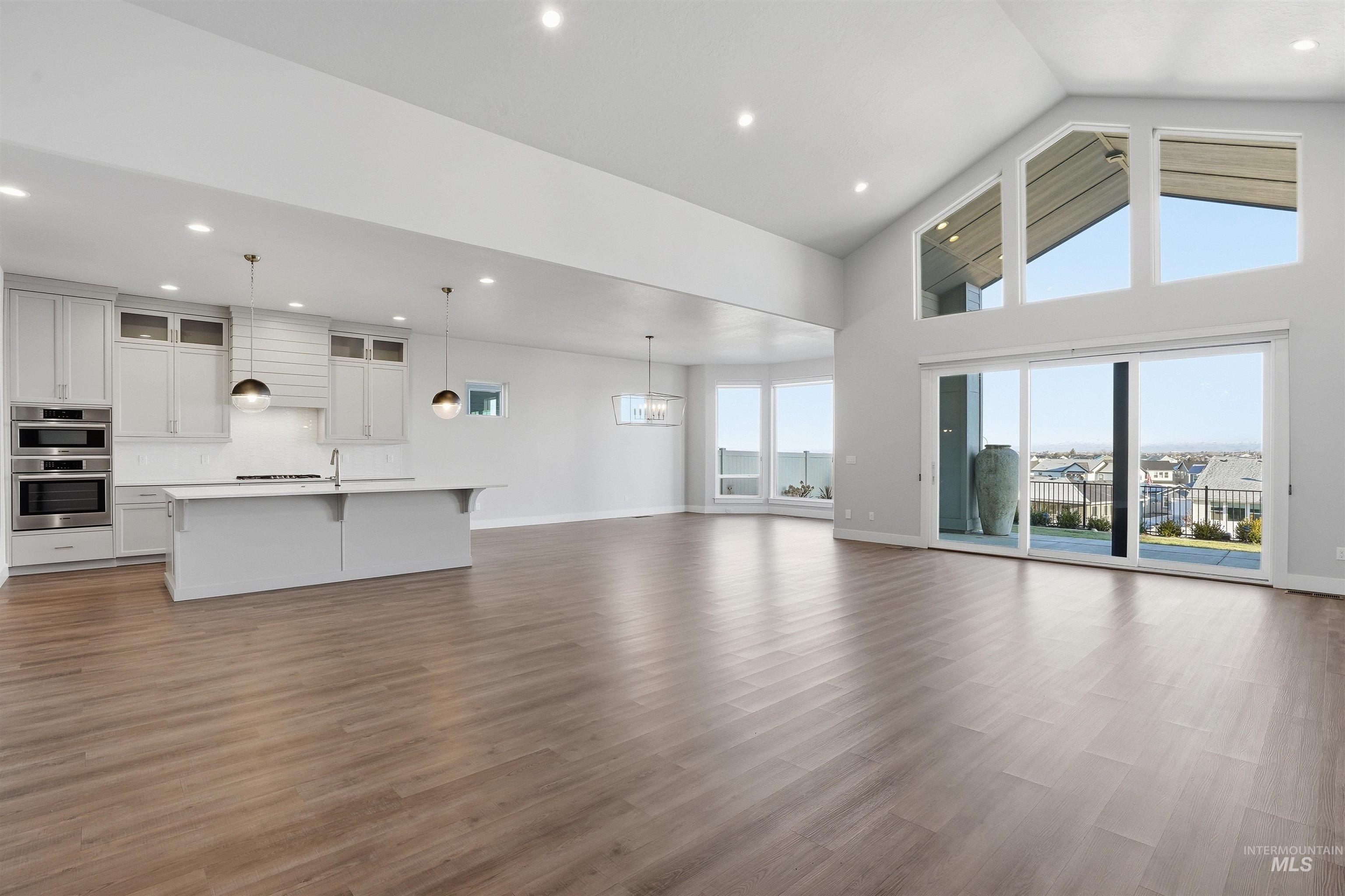 Unfurnished living room featuring dark wood-style flooring, recessed lighting, and high vaulted ceiling