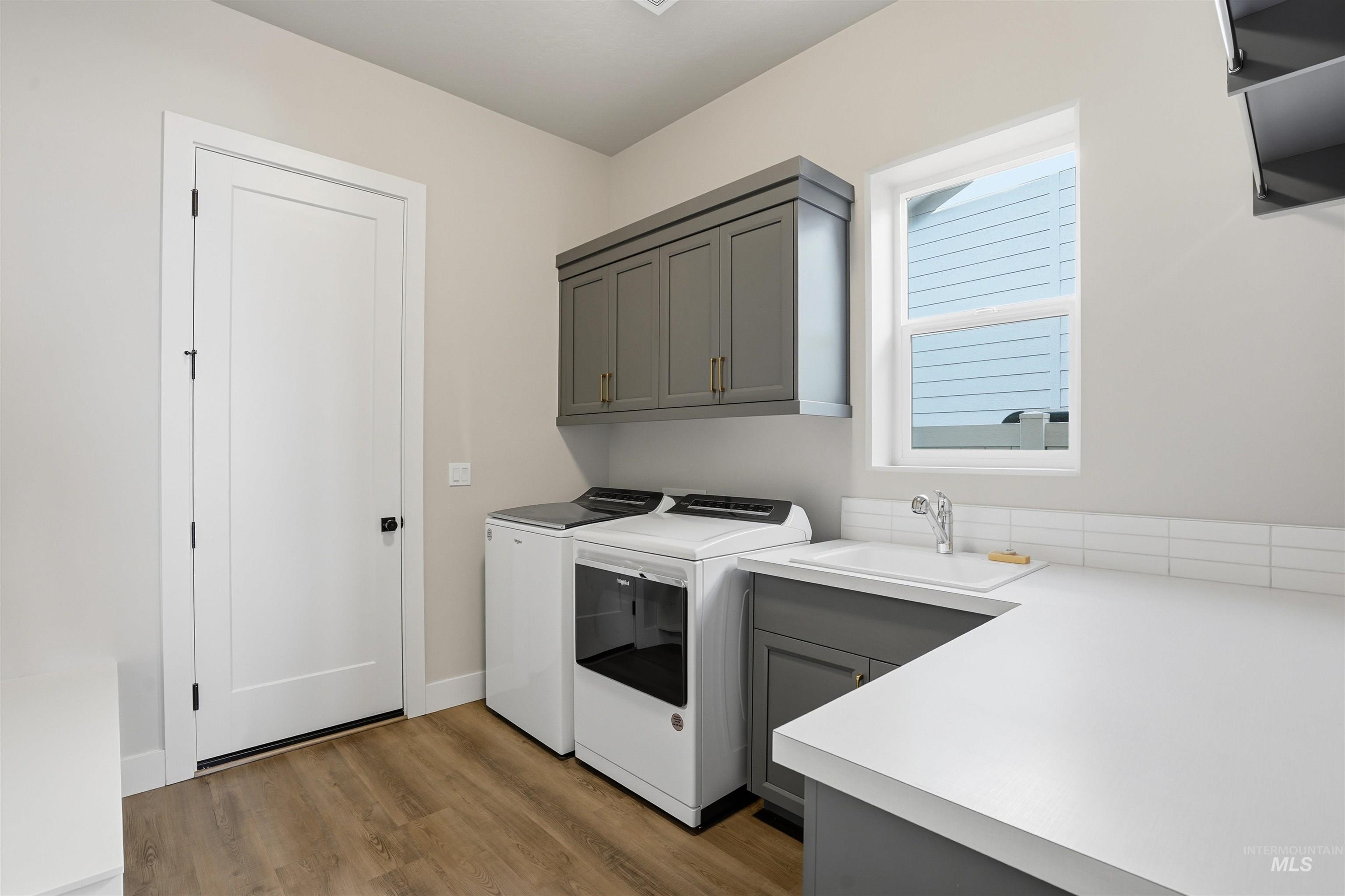 Laundry area featuring washing machine and dryer, dark wood-style flooring, and cabinet space