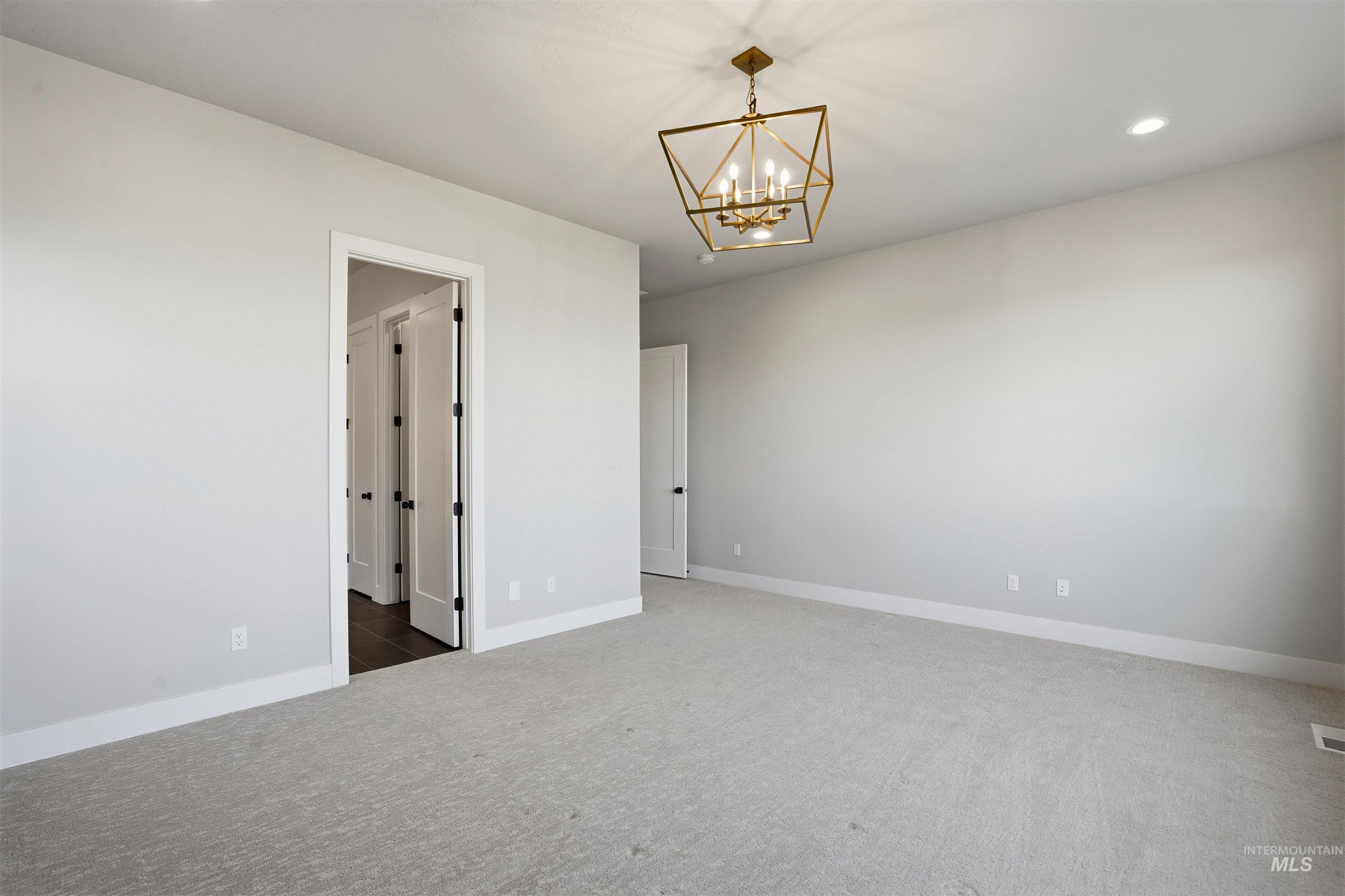 Carpeted spare room with recessed lighting and a chandelier