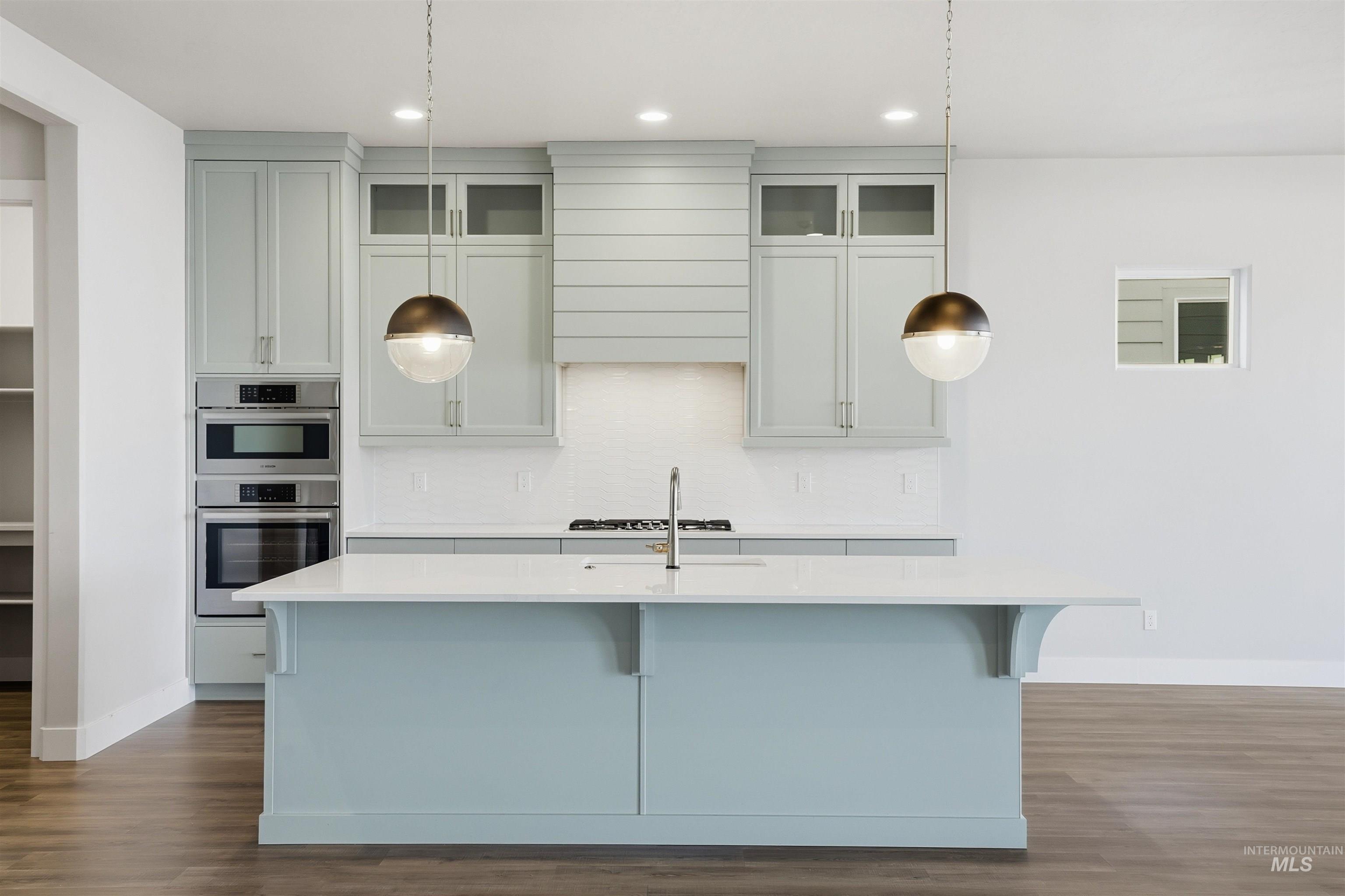 Kitchen featuring glass insert cabinets, dark wood-style flooring, a kitchen bar, light stone countertops, and recessed lighting