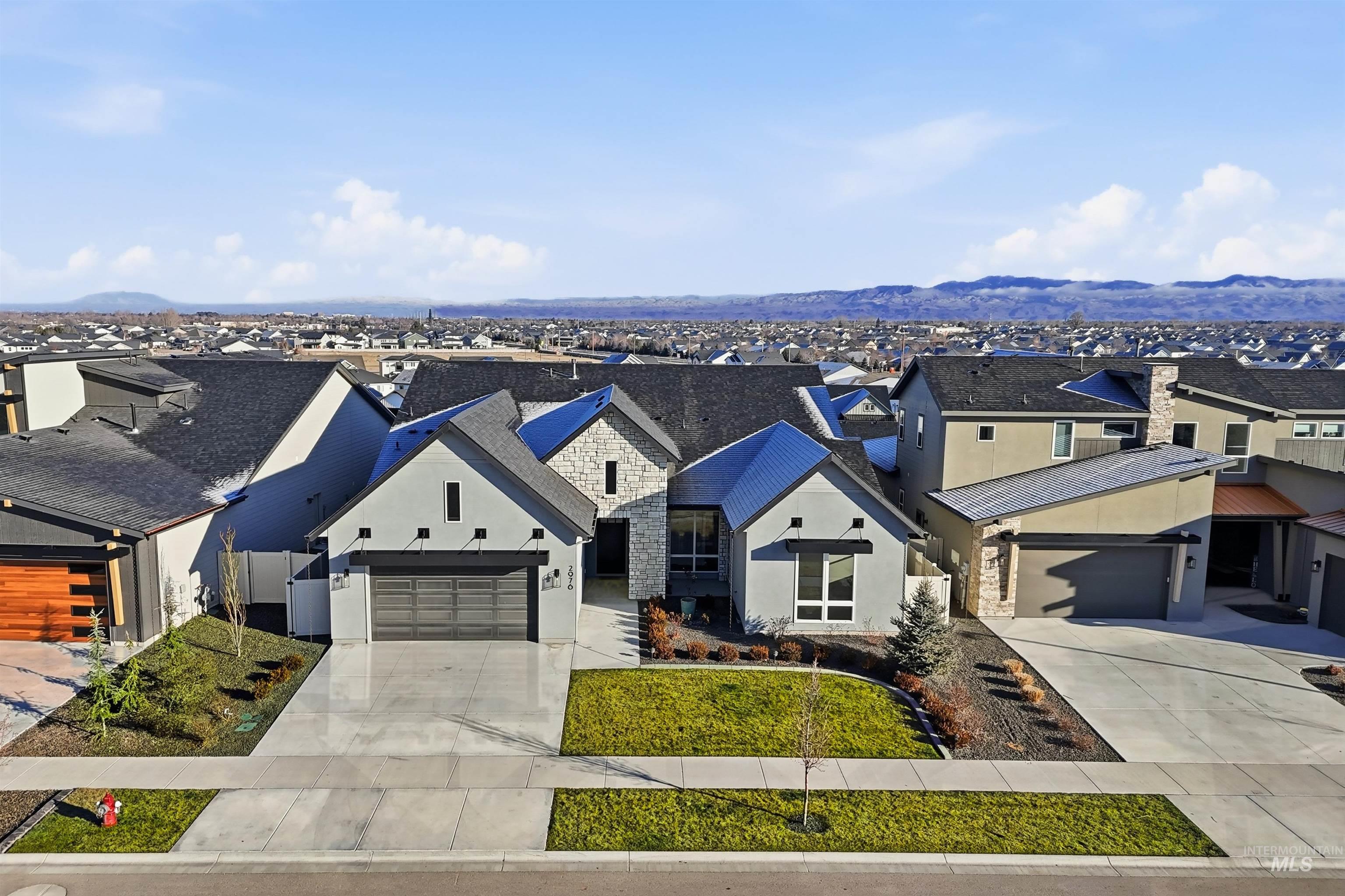 View of front of property featuring a residential view, driveway, stone siding, and stucco siding