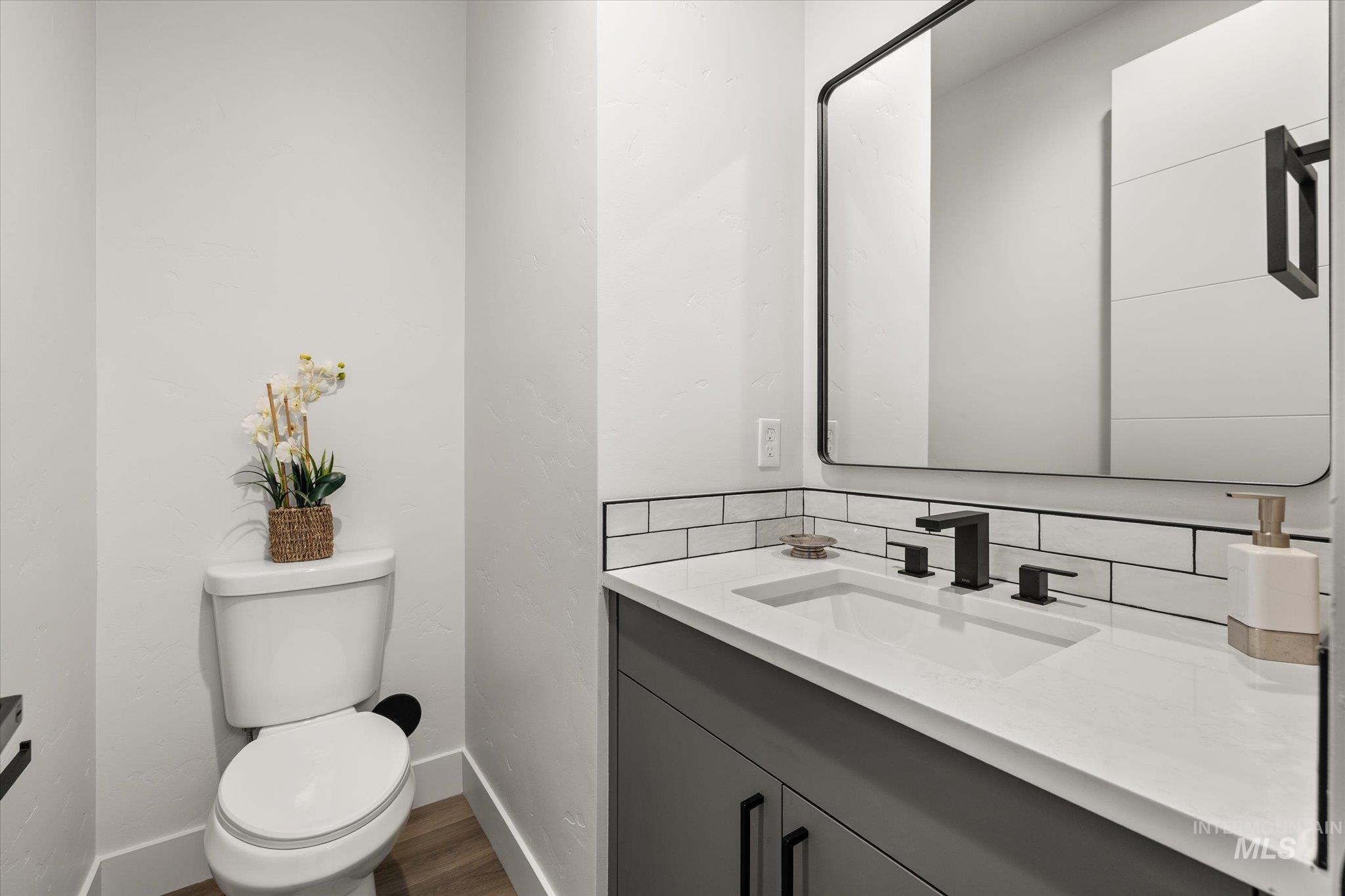 Half bath with vanity, dark wood-style floors, and tasteful backsplash