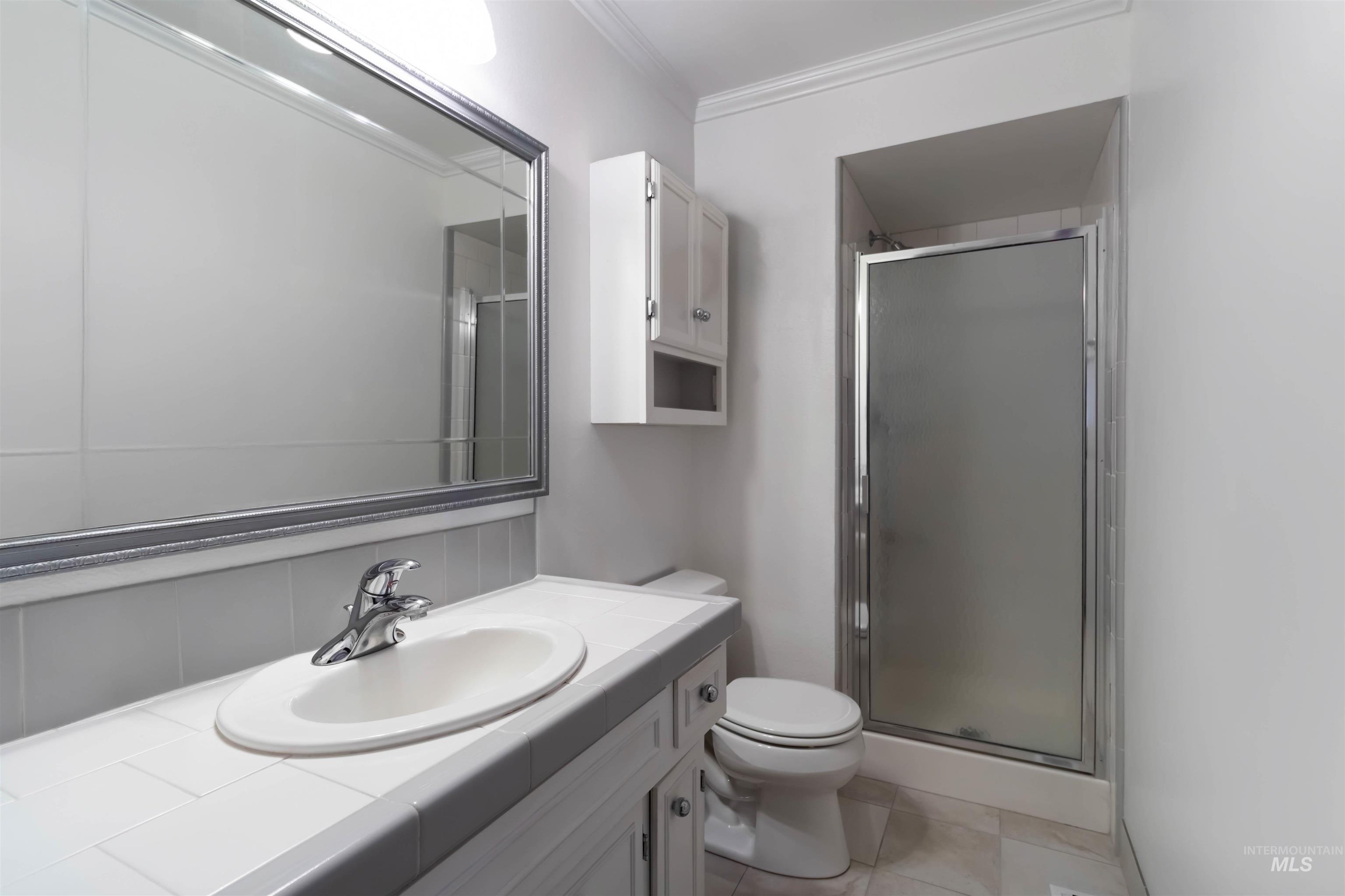 Bathroom with vanity, ornamental molding, a shower stall, and light tile patterned flooring