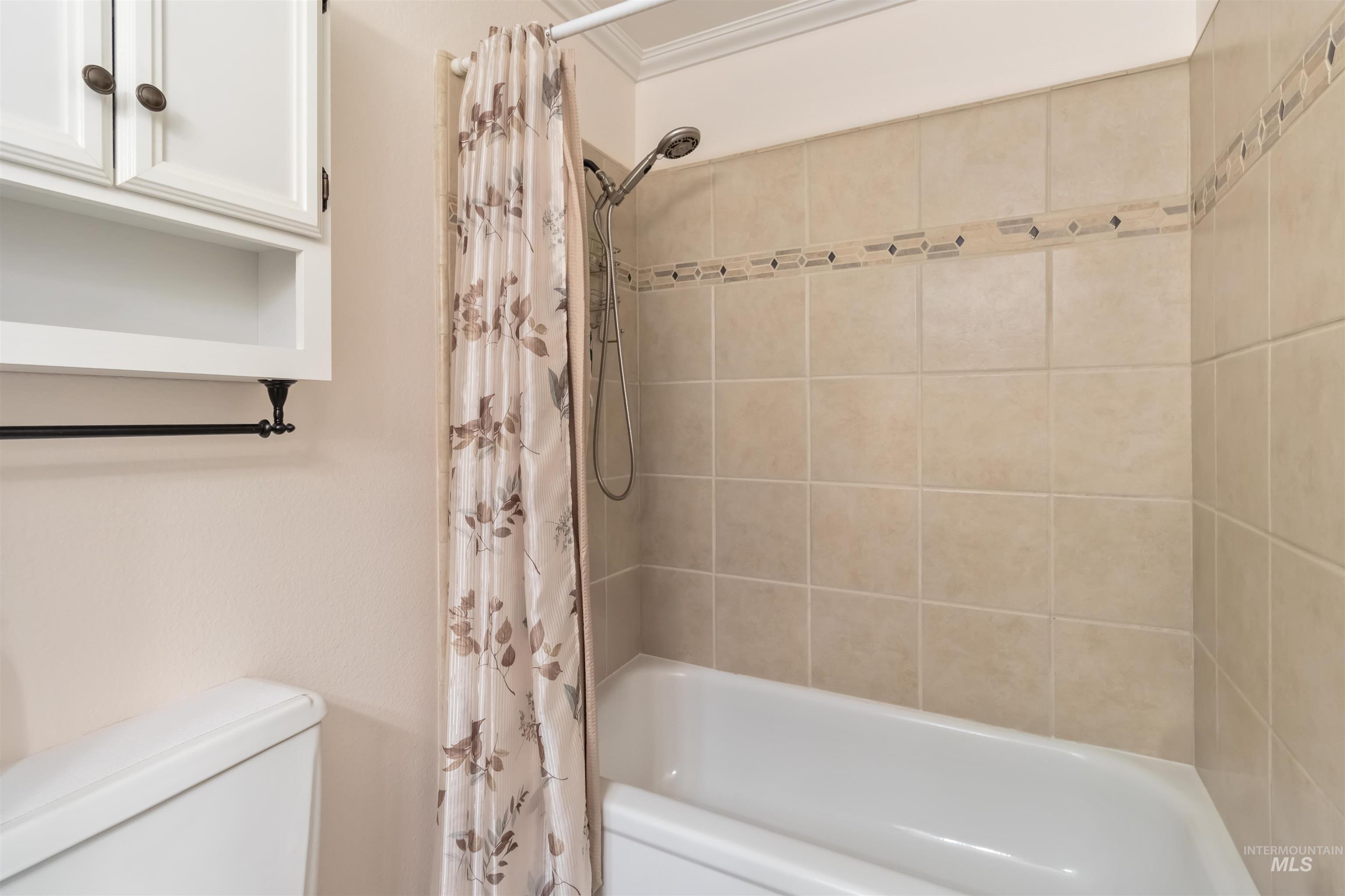 Bathroom with shower / tub combo with curtain and ornamental molding