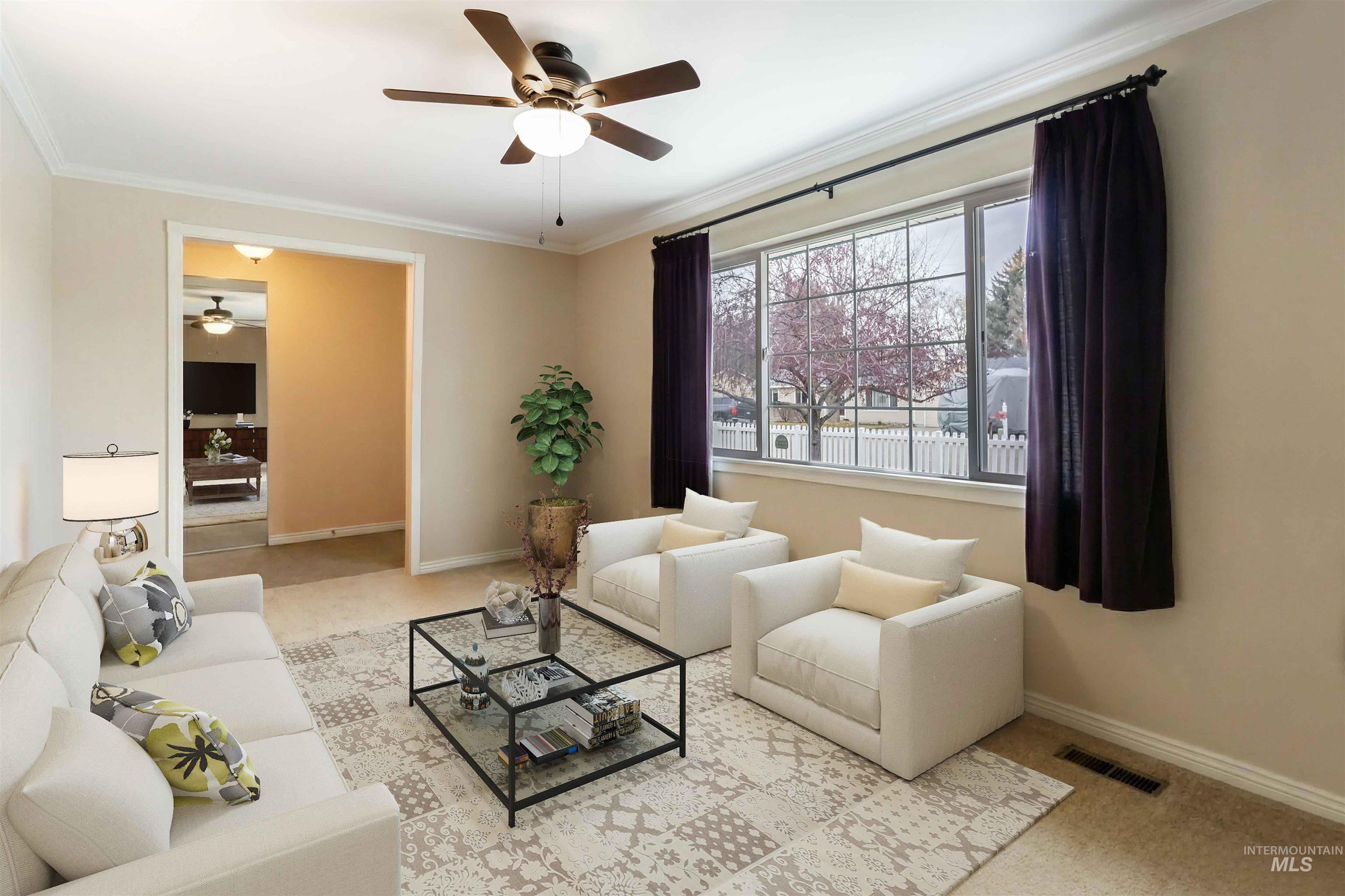 Living area with light colored carpet, a ceiling fan, and ornamental molding
