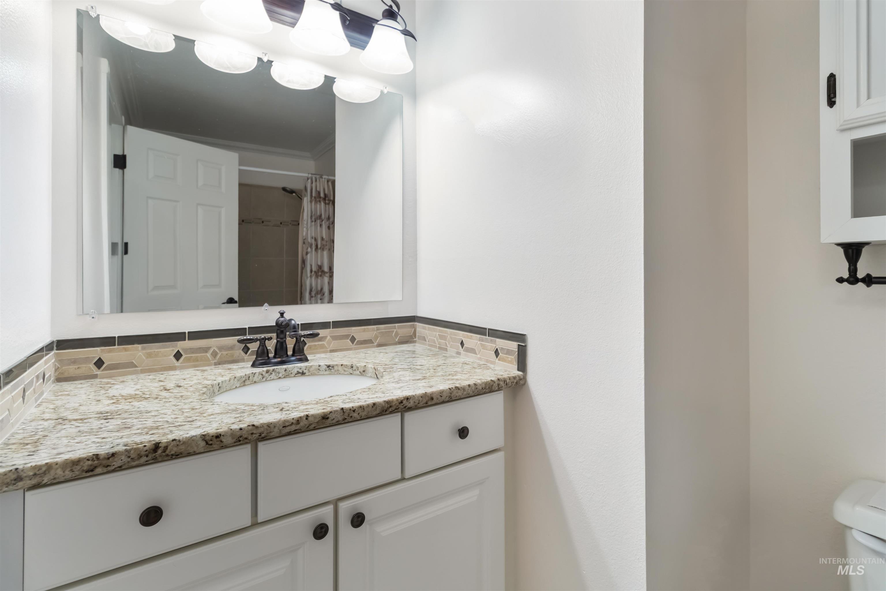 Full bathroom featuring vanity, curtained shower, and backsplash