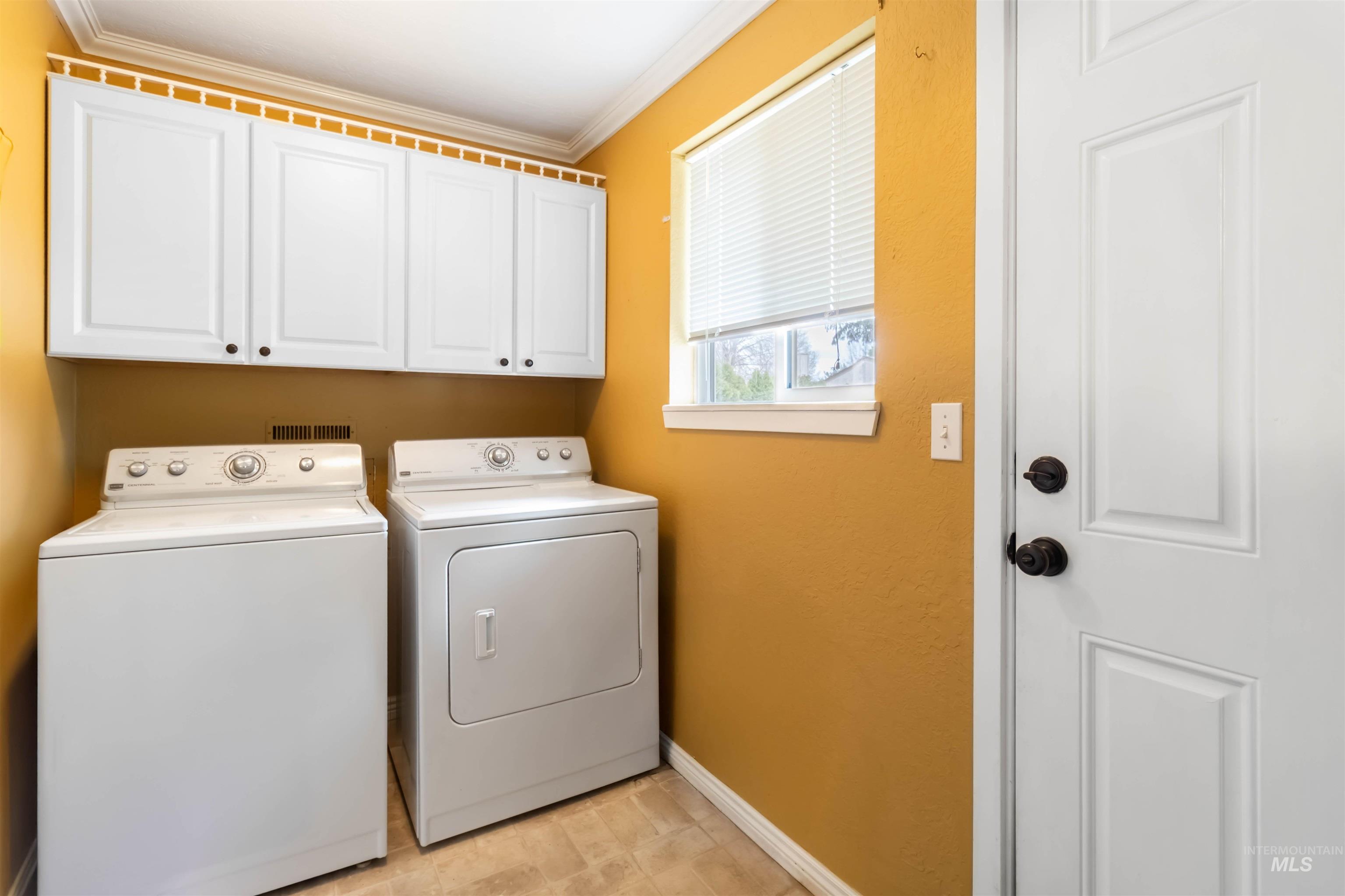 Laundry area with cabinet space, ornamental molding, and washer and clothes dryer