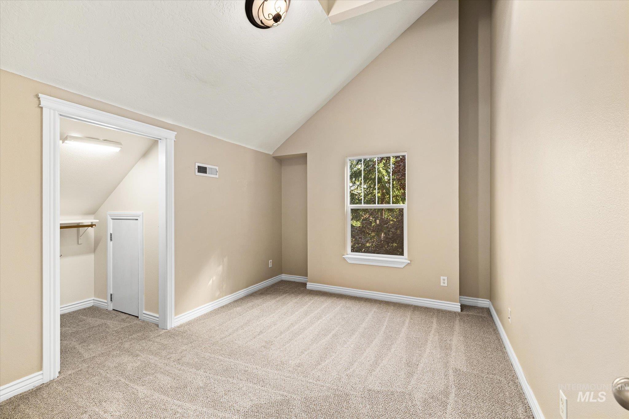 Unfurnished bedroom with lofted ceiling and light colored carpet