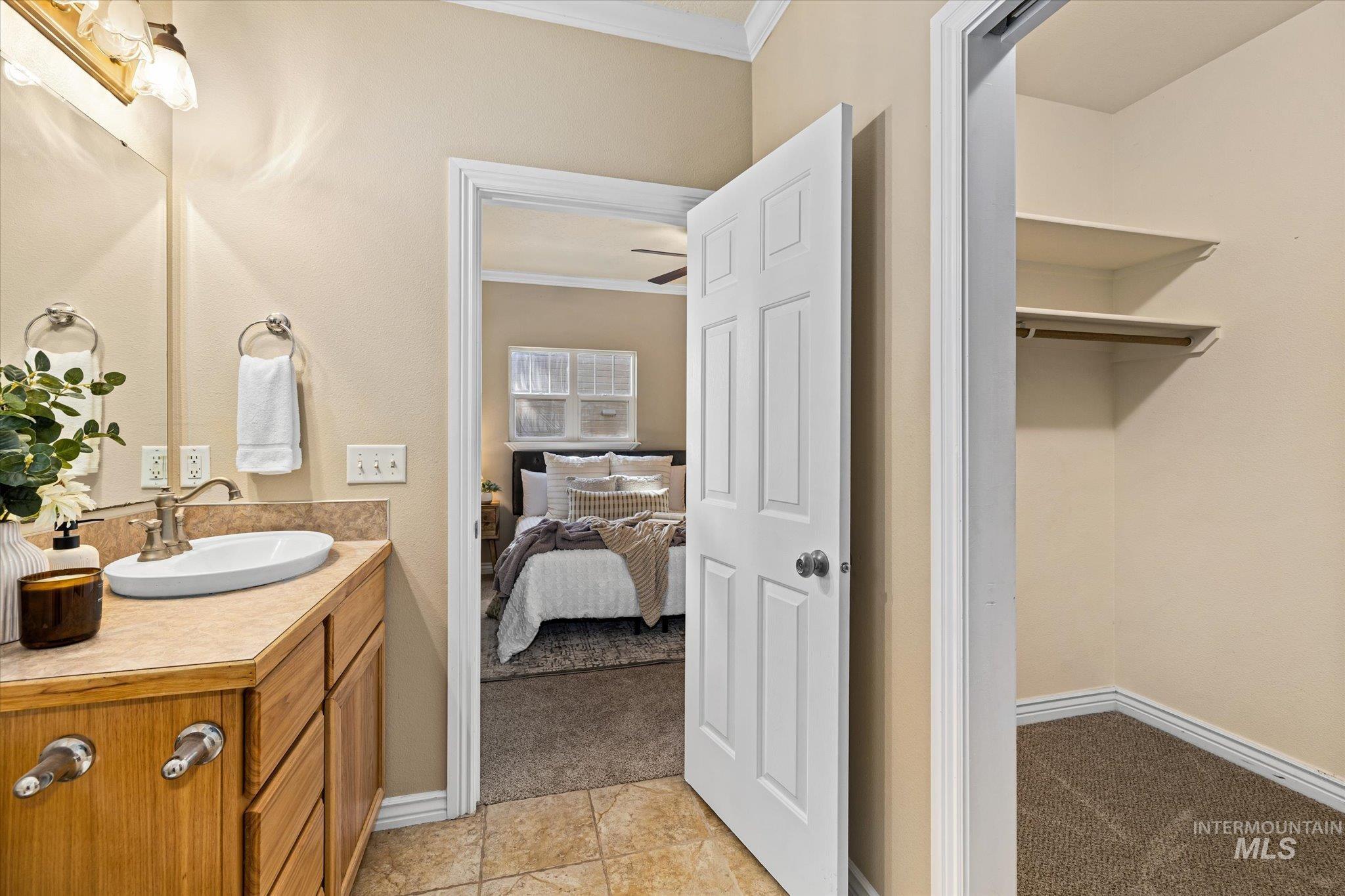Bathroom with crown molding, vanity, light tile patterned floors, ensuite bathroom, and a ceiling fan