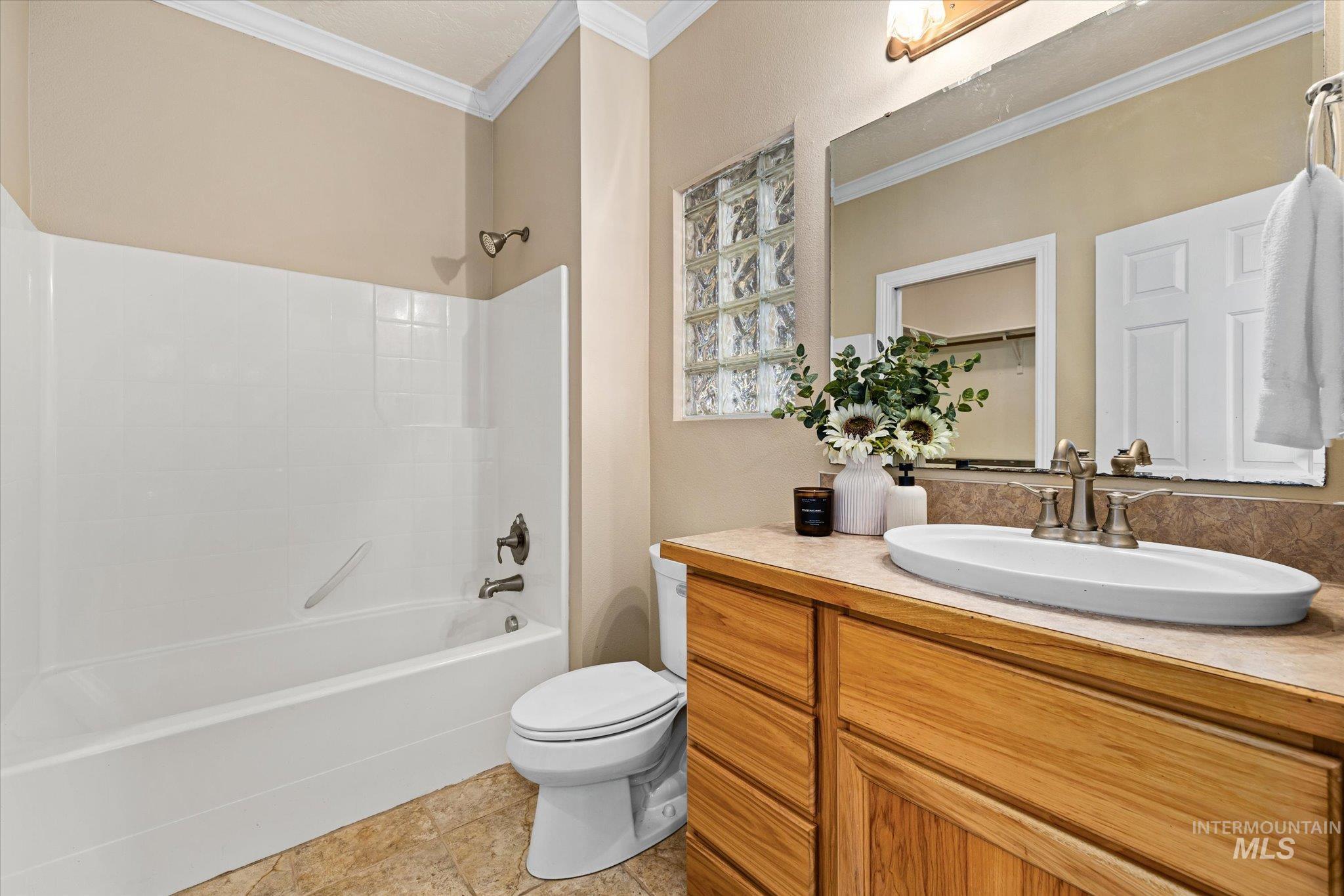 Full bathroom featuring washtub / shower combination, ornamental molding, vanity, and light tile patterned flooring