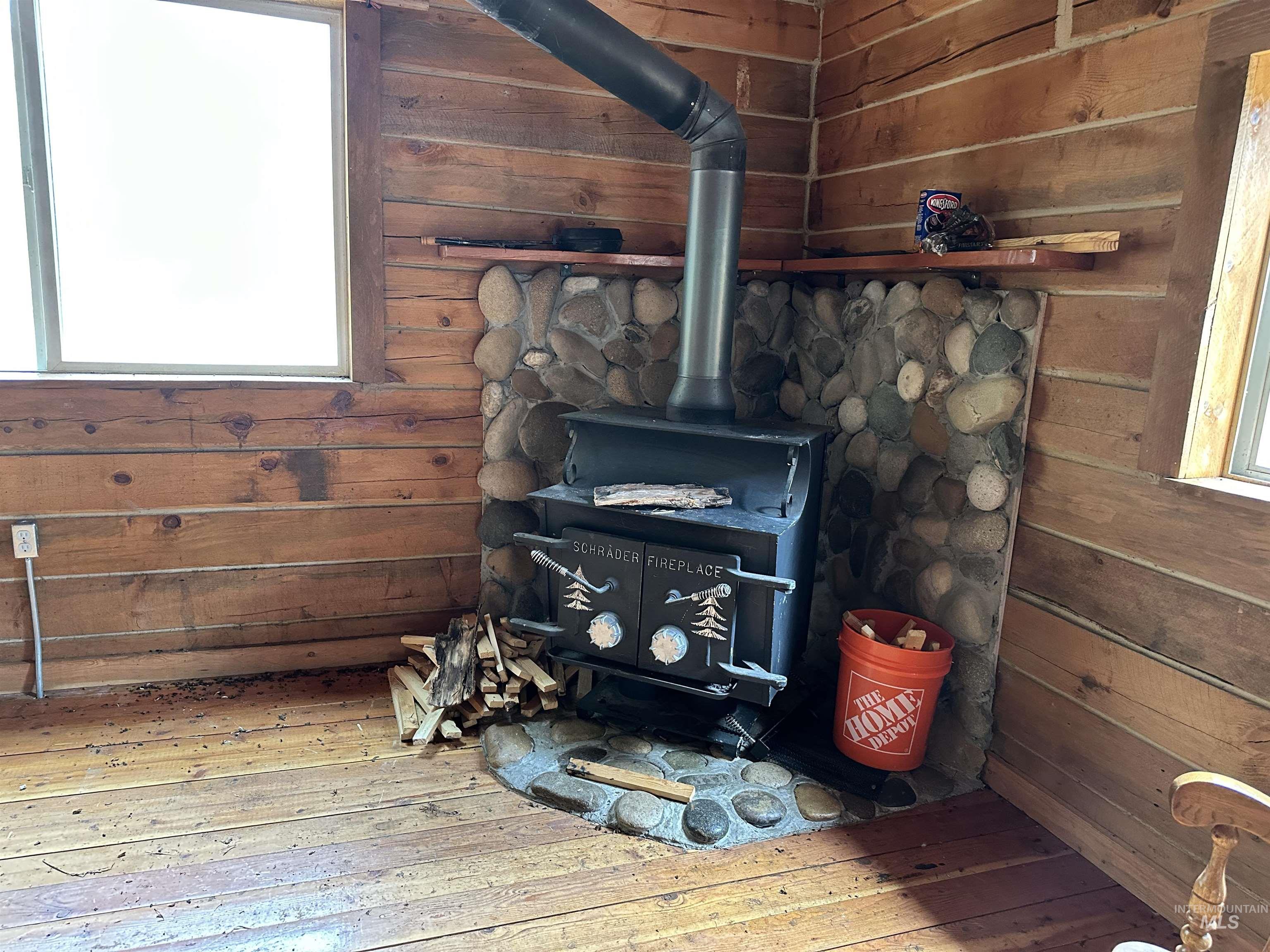 Detailed view of a wood stove, wood walls, and wood finished floors