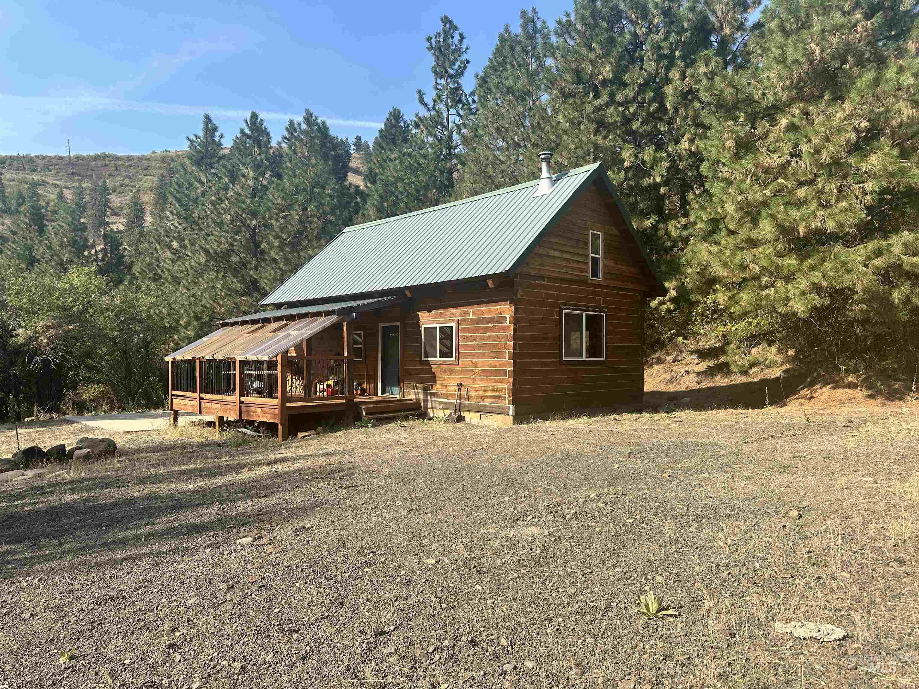 View of property exterior featuring a metal roof, a porch, and a forest view