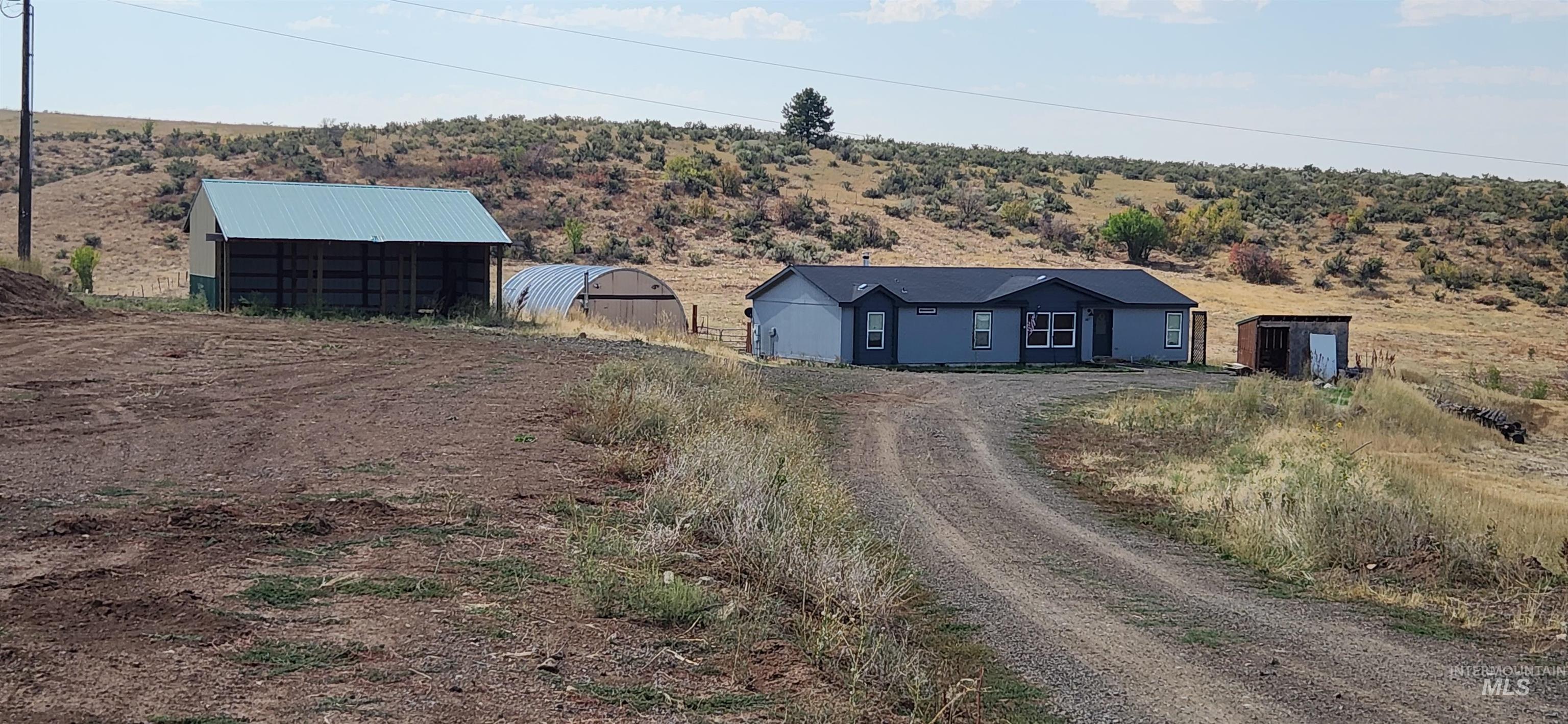 View of front of property featuring a pole building, an outbuilding, driveway, and a rural view