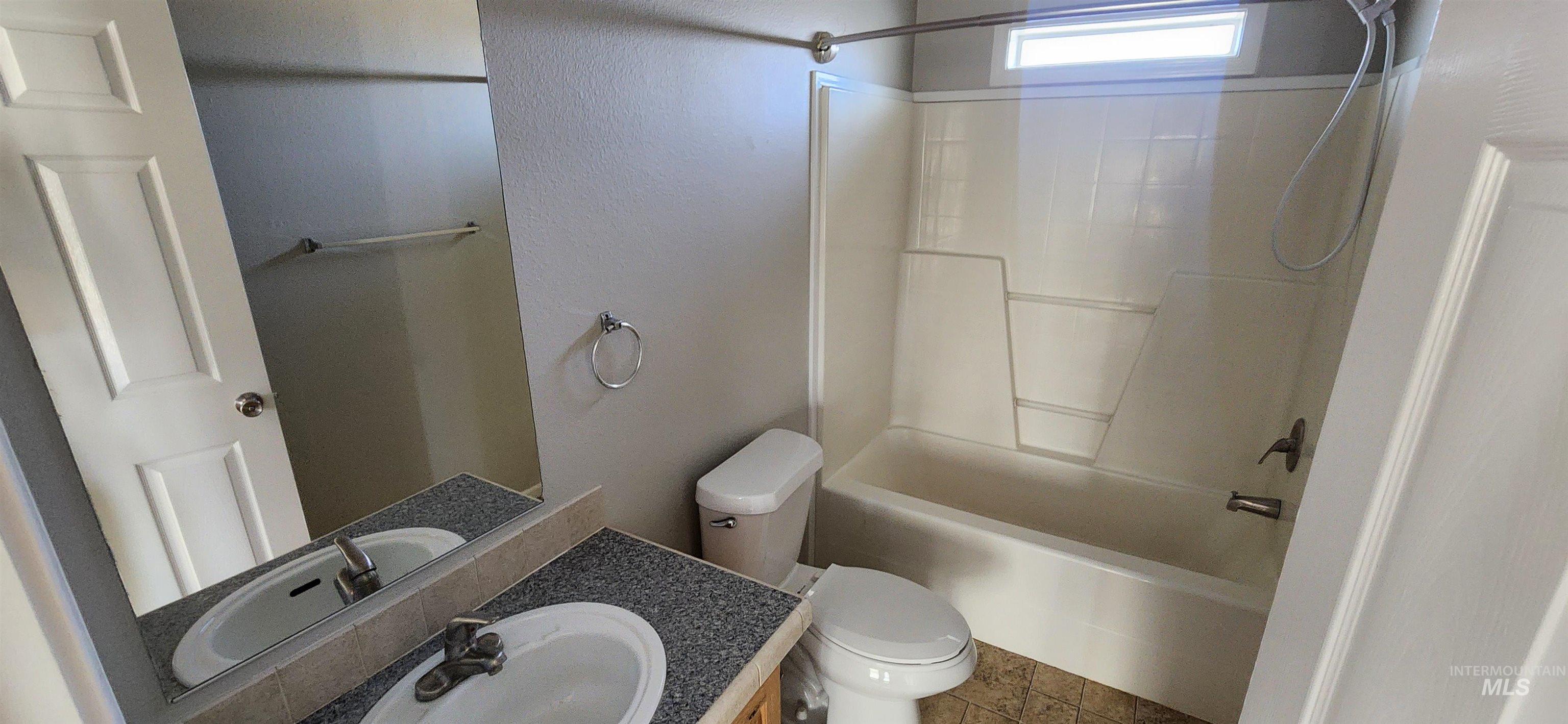 Bathroom with bathing tub / shower combination, vanity, a textured wall, and tile patterned floors