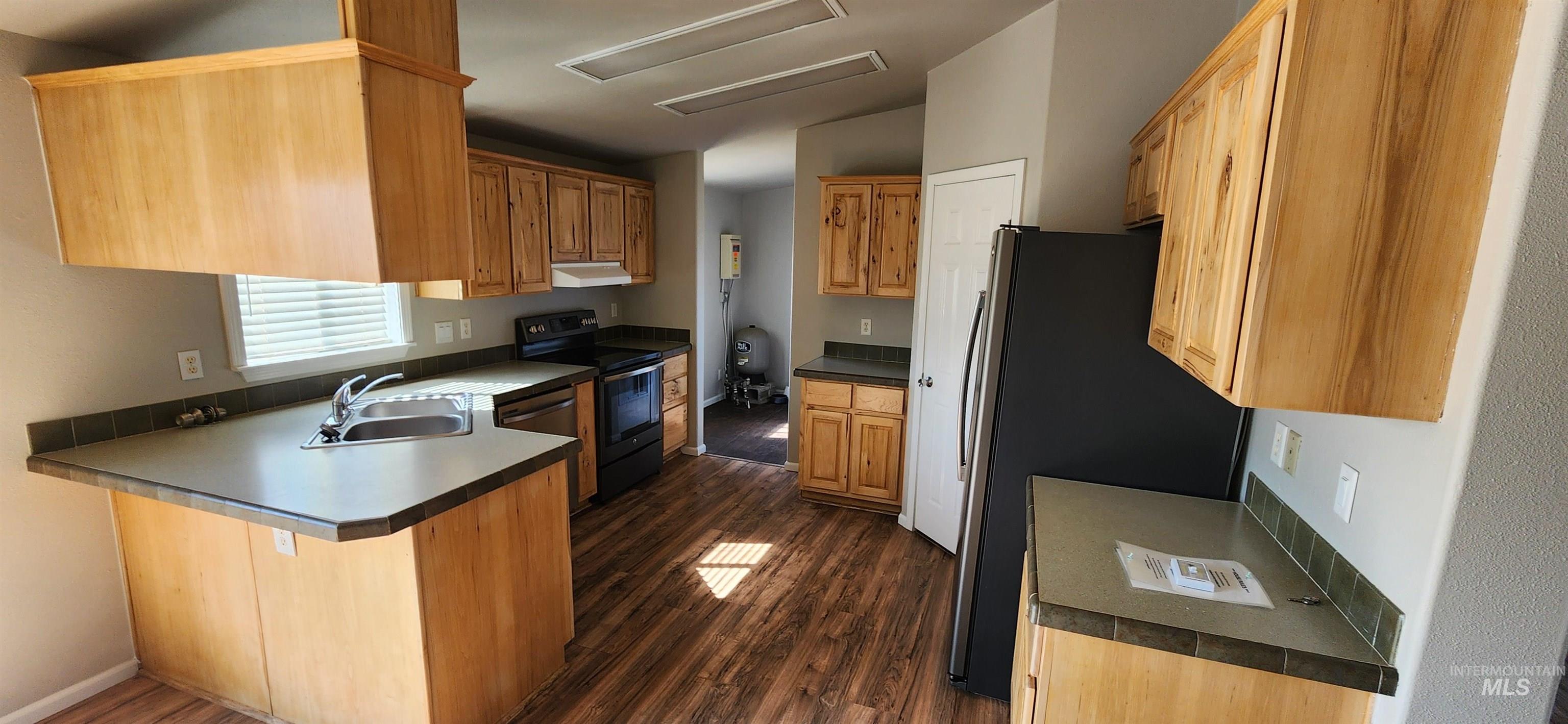 Kitchen with dark wood-style floors, a peninsula, black electric range oven, and dark countertops