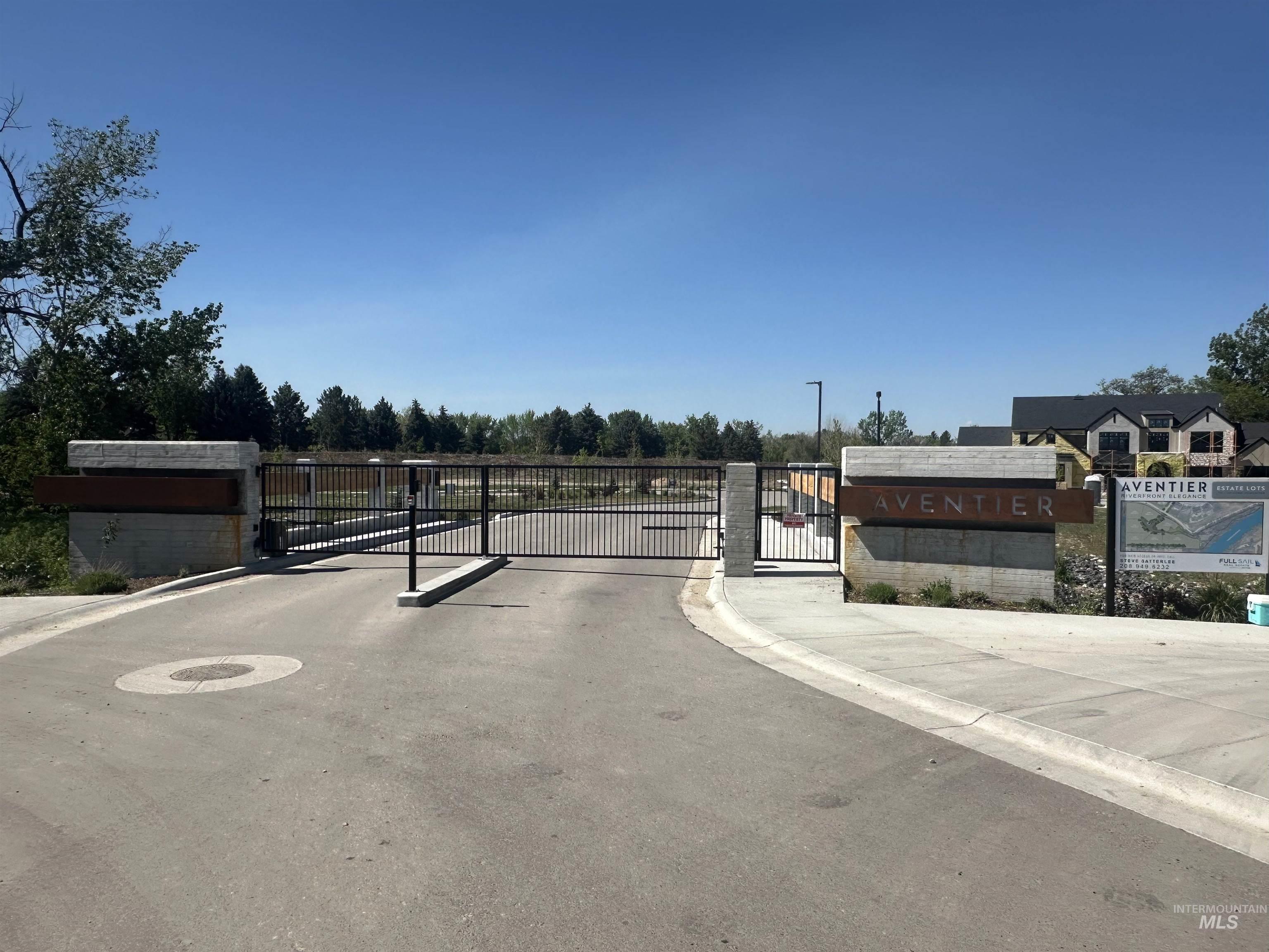 View of asphalt road with curbs, a gate, a gated entry, and sidewalks