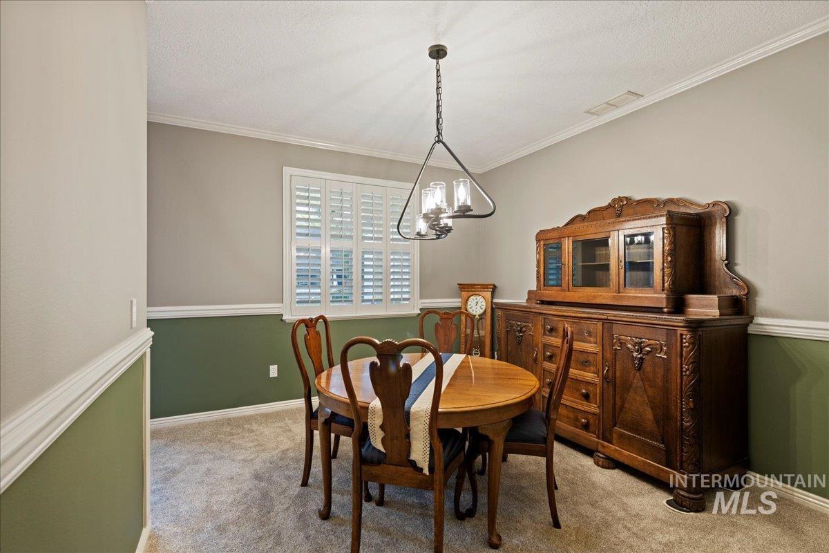 Dining area featuring ornamental molding, carpet, a chandelier, and a textured ceiling
