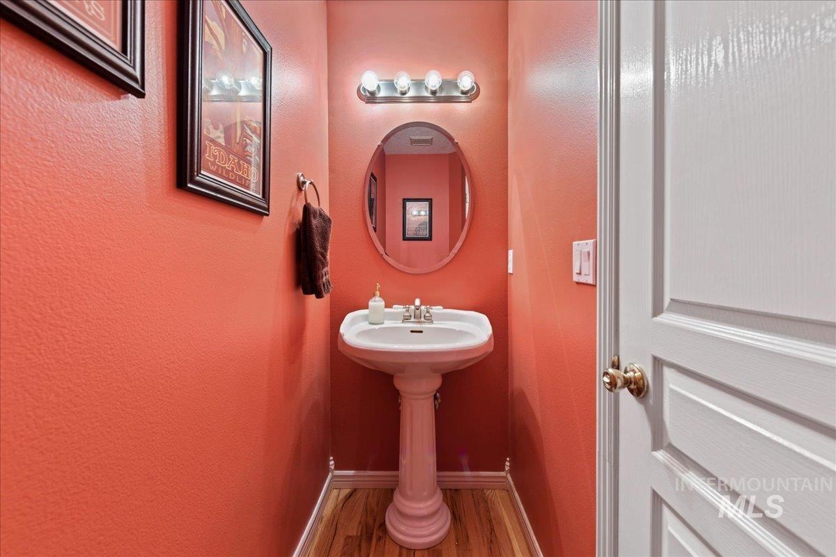 Half bathroom with wood finished floors and a textured wall